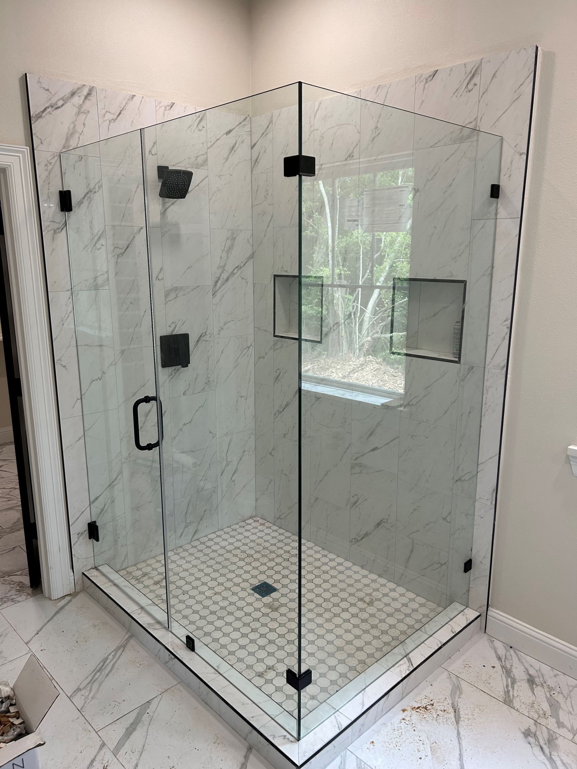 A bathroom with a shower stall and a window.