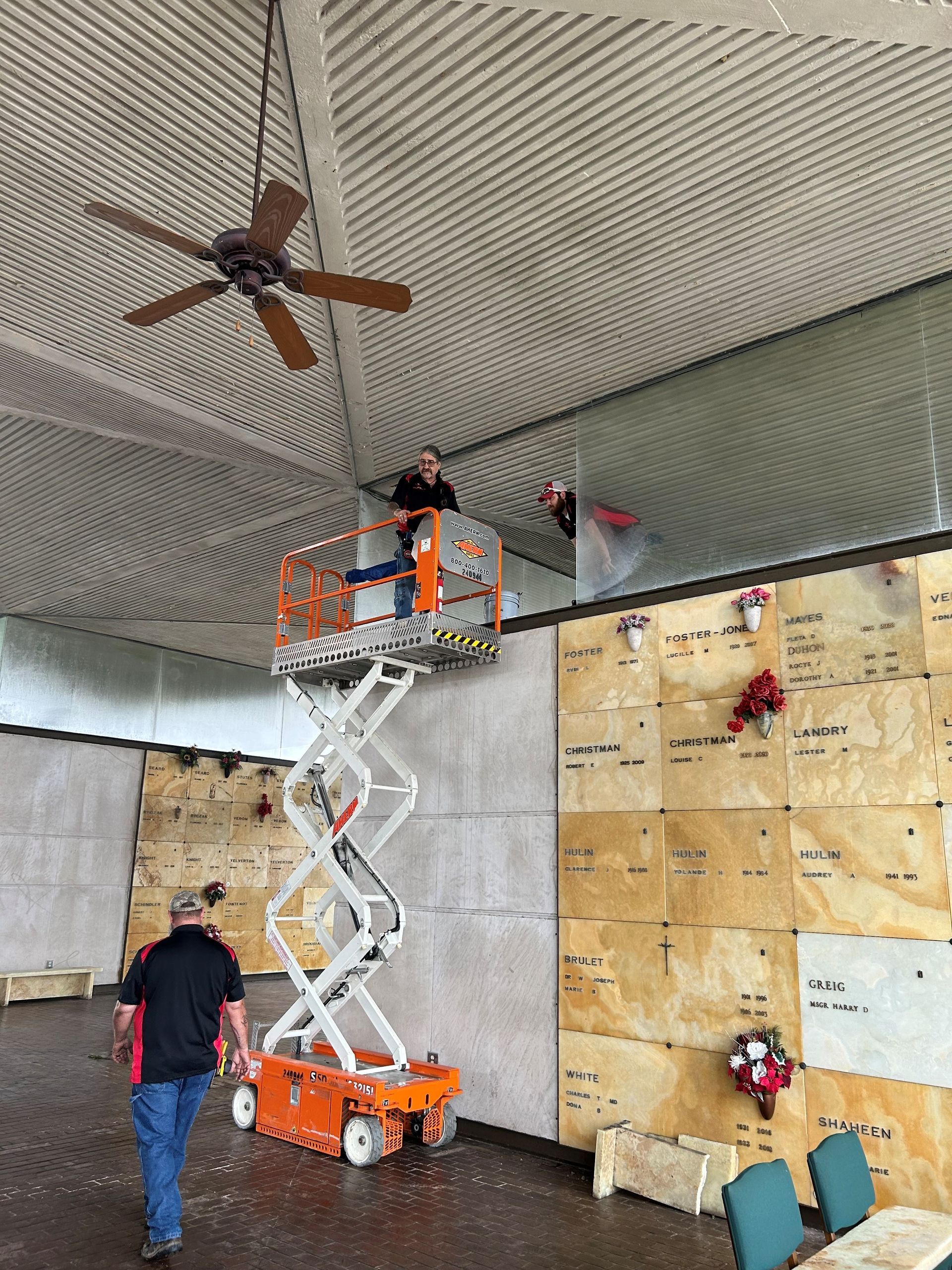 A man is standing next to a scissor lift in a room.