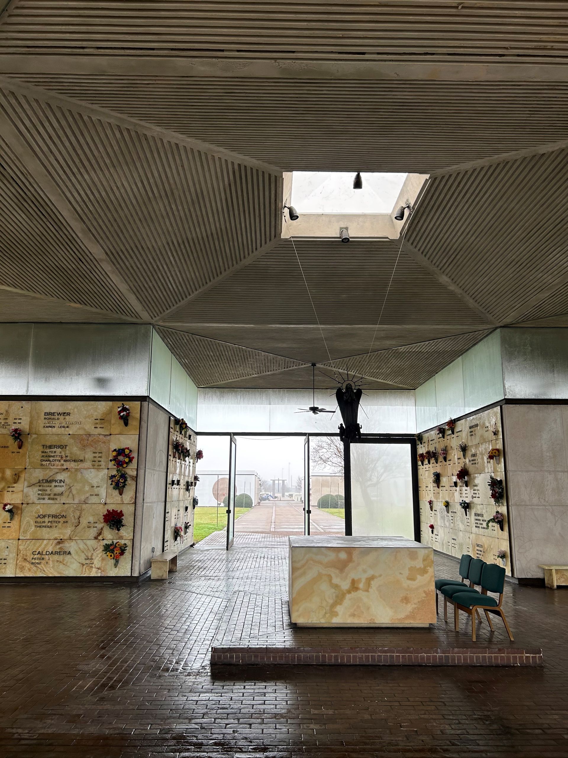 The inside of a cemetery with a table and chairs and a skylight in the ceiling.