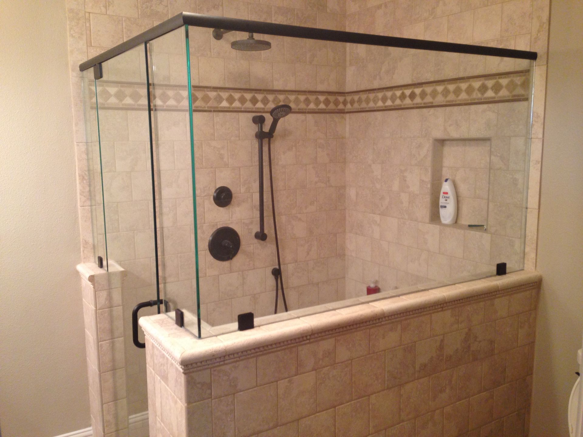 A bathroom with a walk in shower with a glass door.