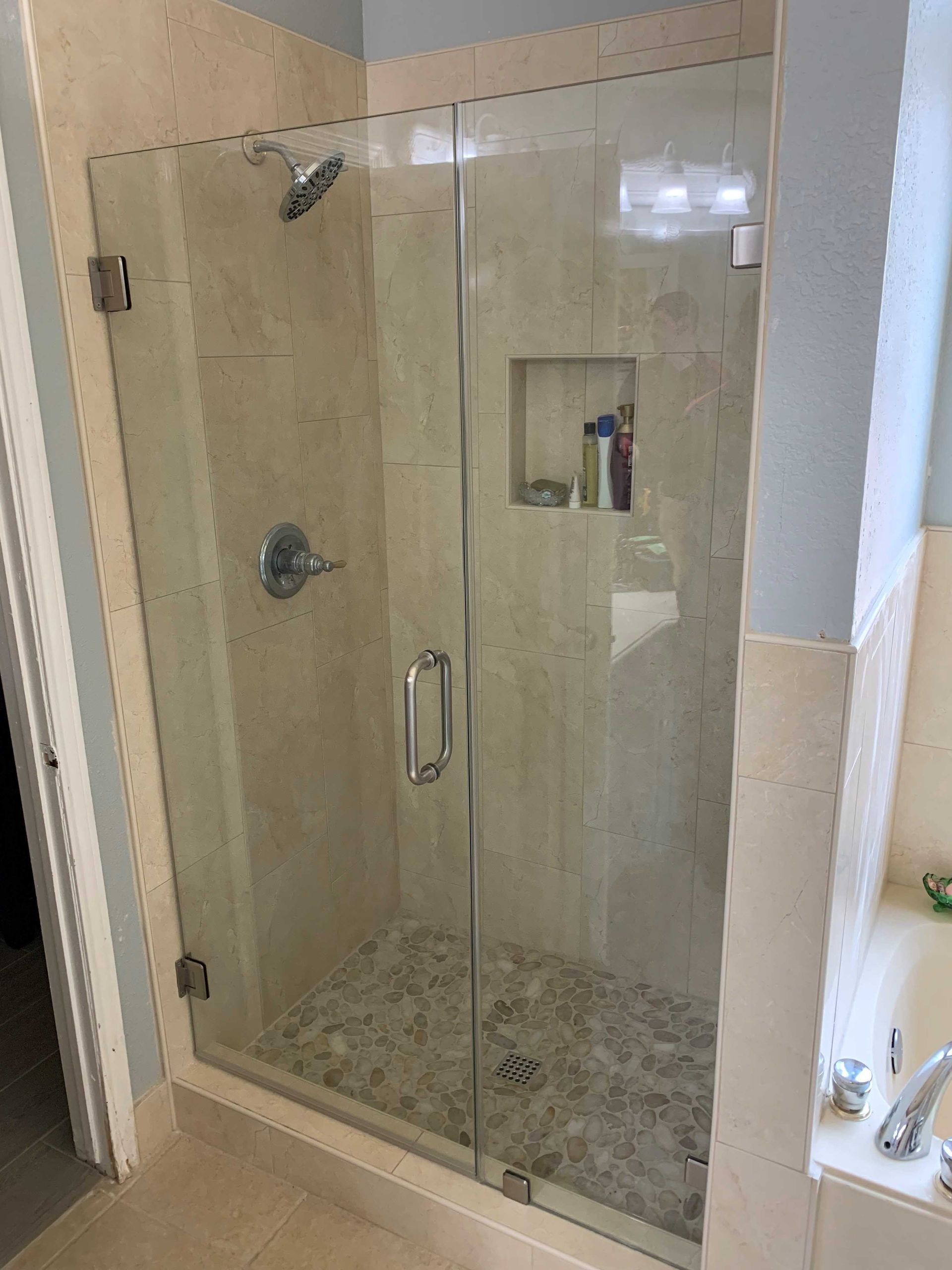 A bathroom with a walk in shower with a glass door.