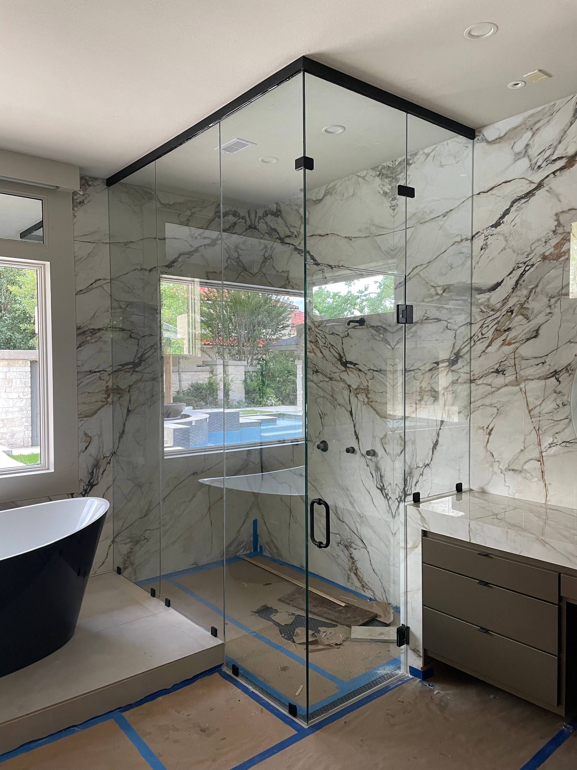 A bathroom with a bathtub , shower , and marble wall.