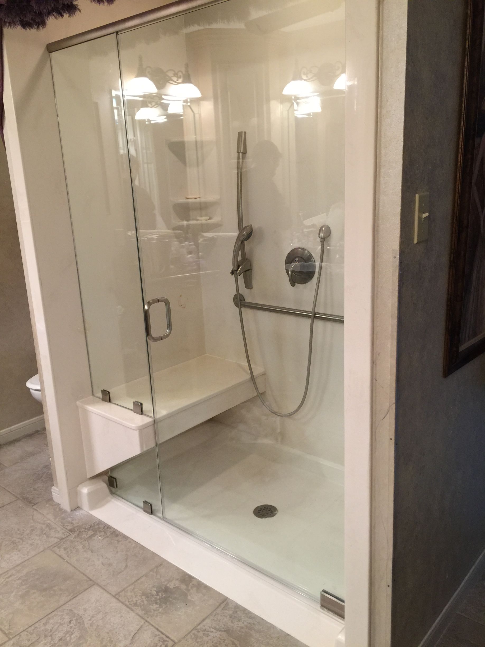 A bathroom with a walk in shower with a glass door.
