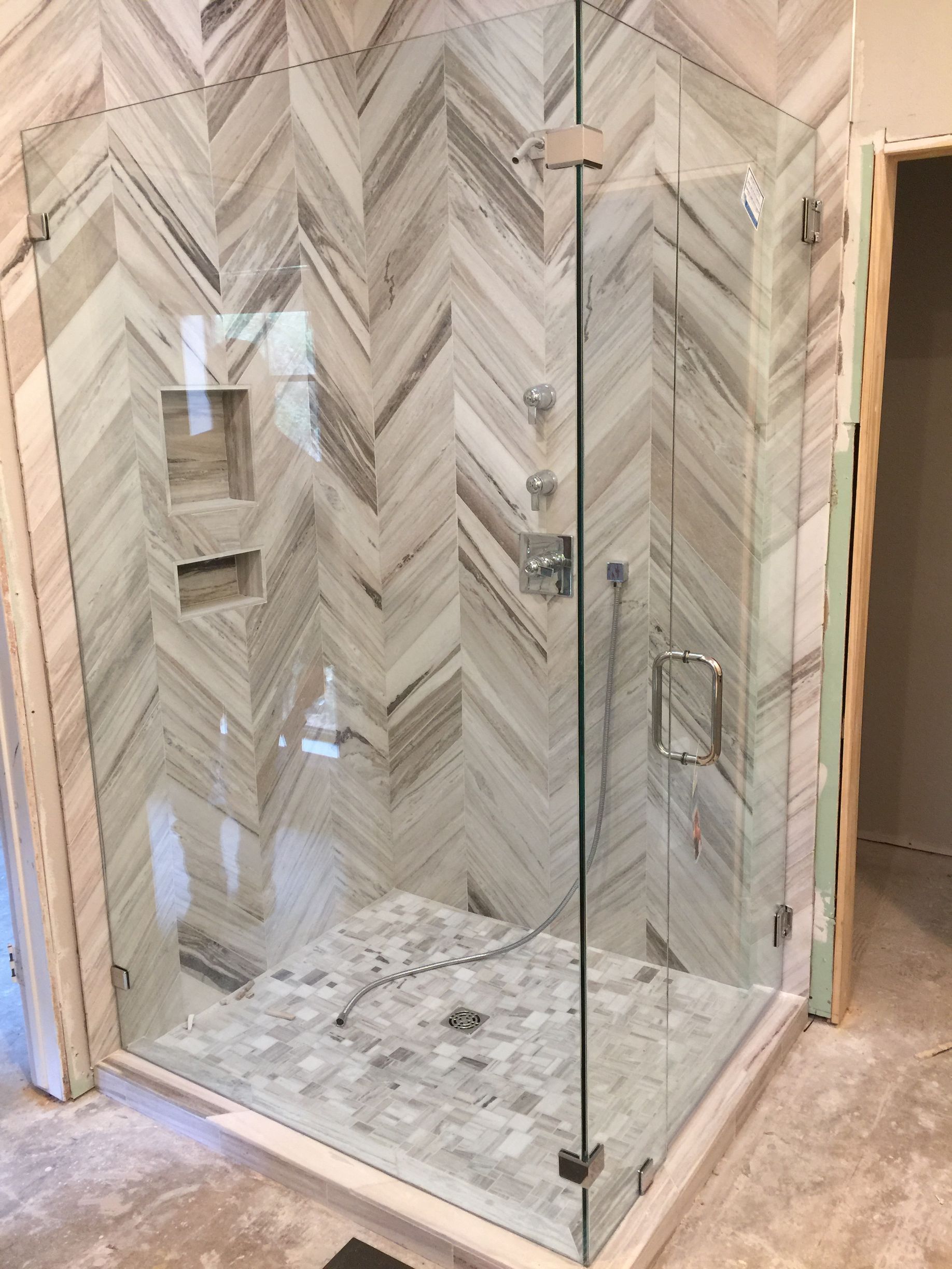 A bathroom with a walk in shower with a glass door.
