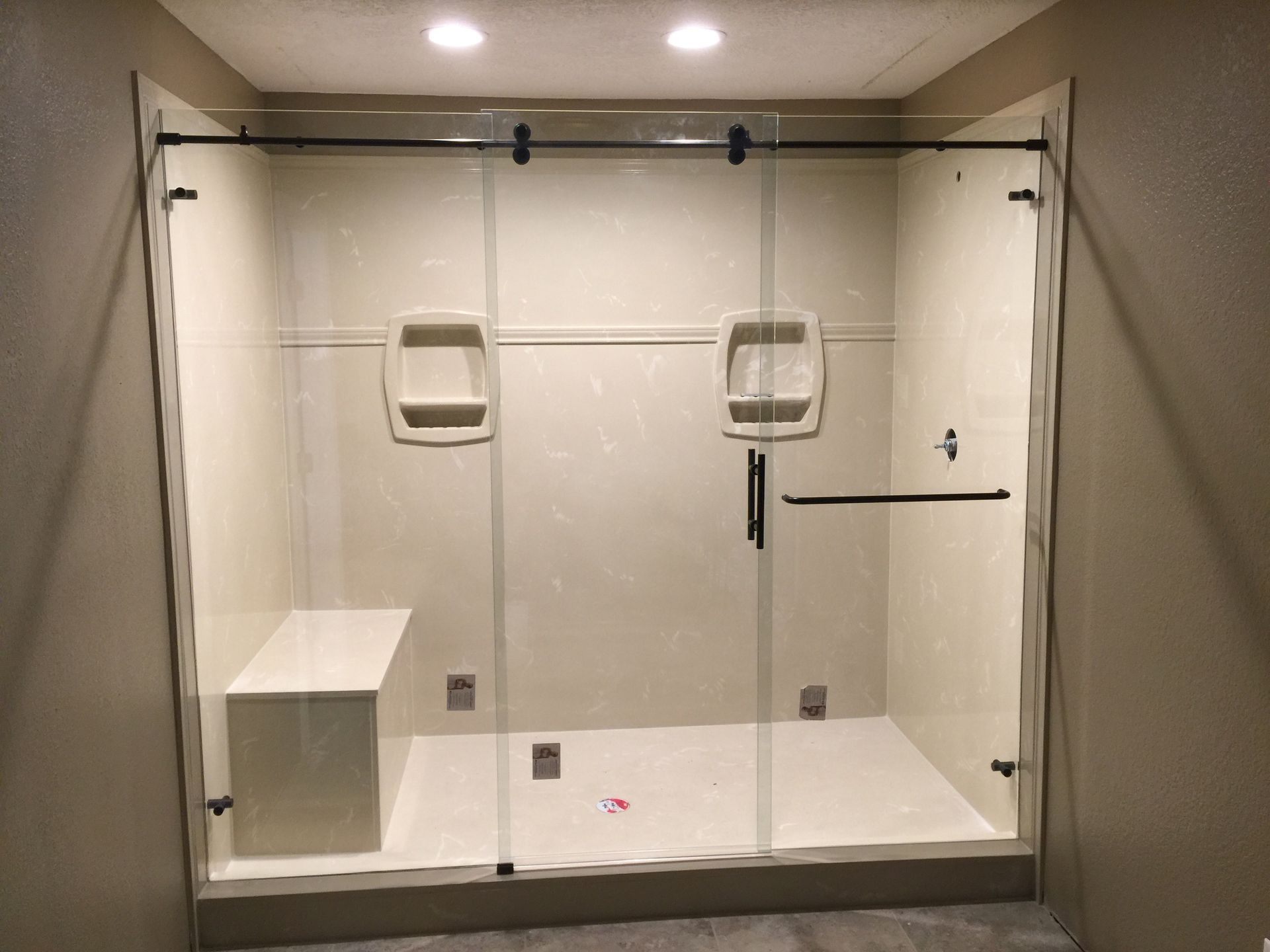 A bathroom with a sliding glass shower door and a bench.