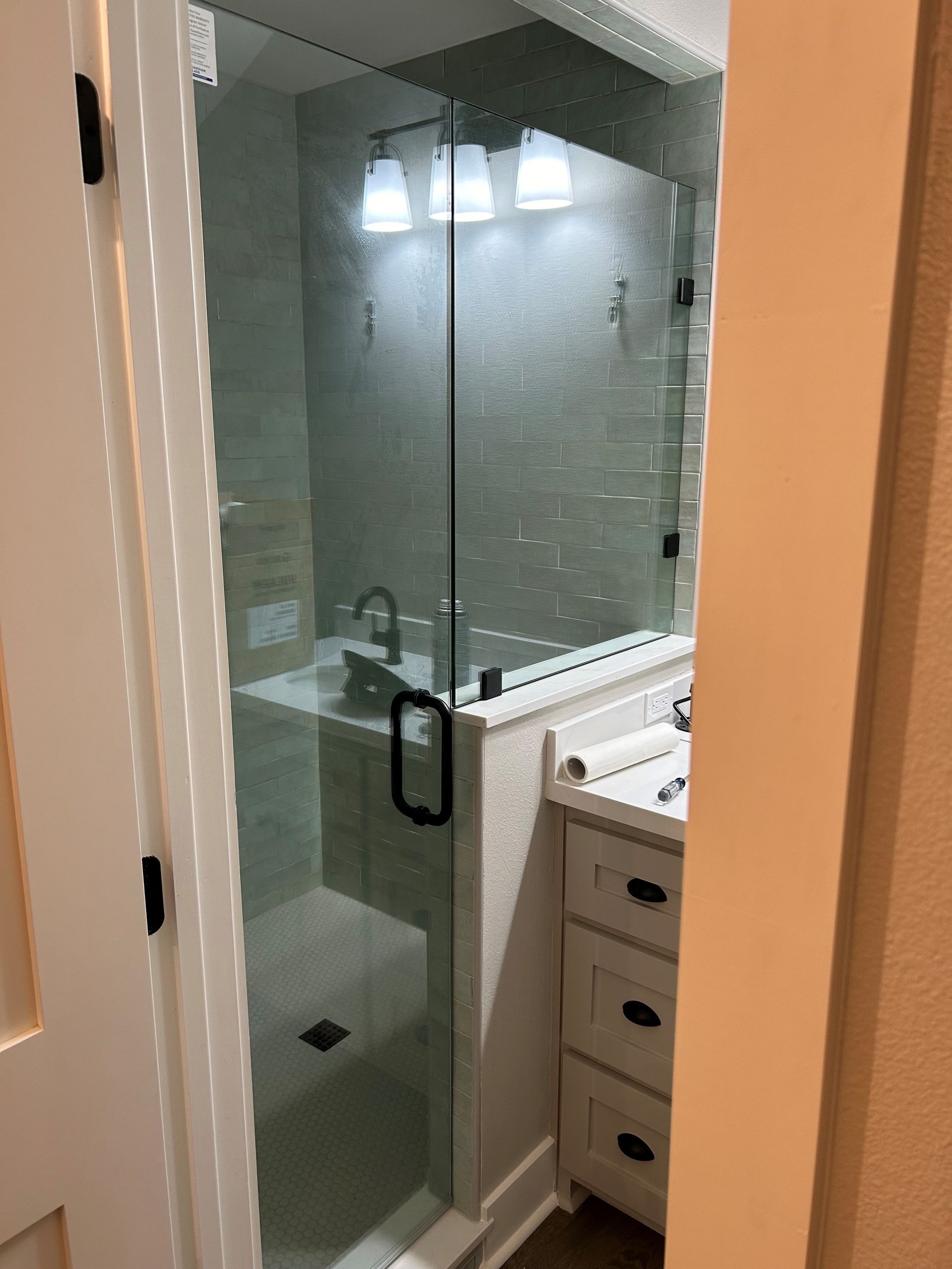 A bathroom with a glass shower door and a sink
