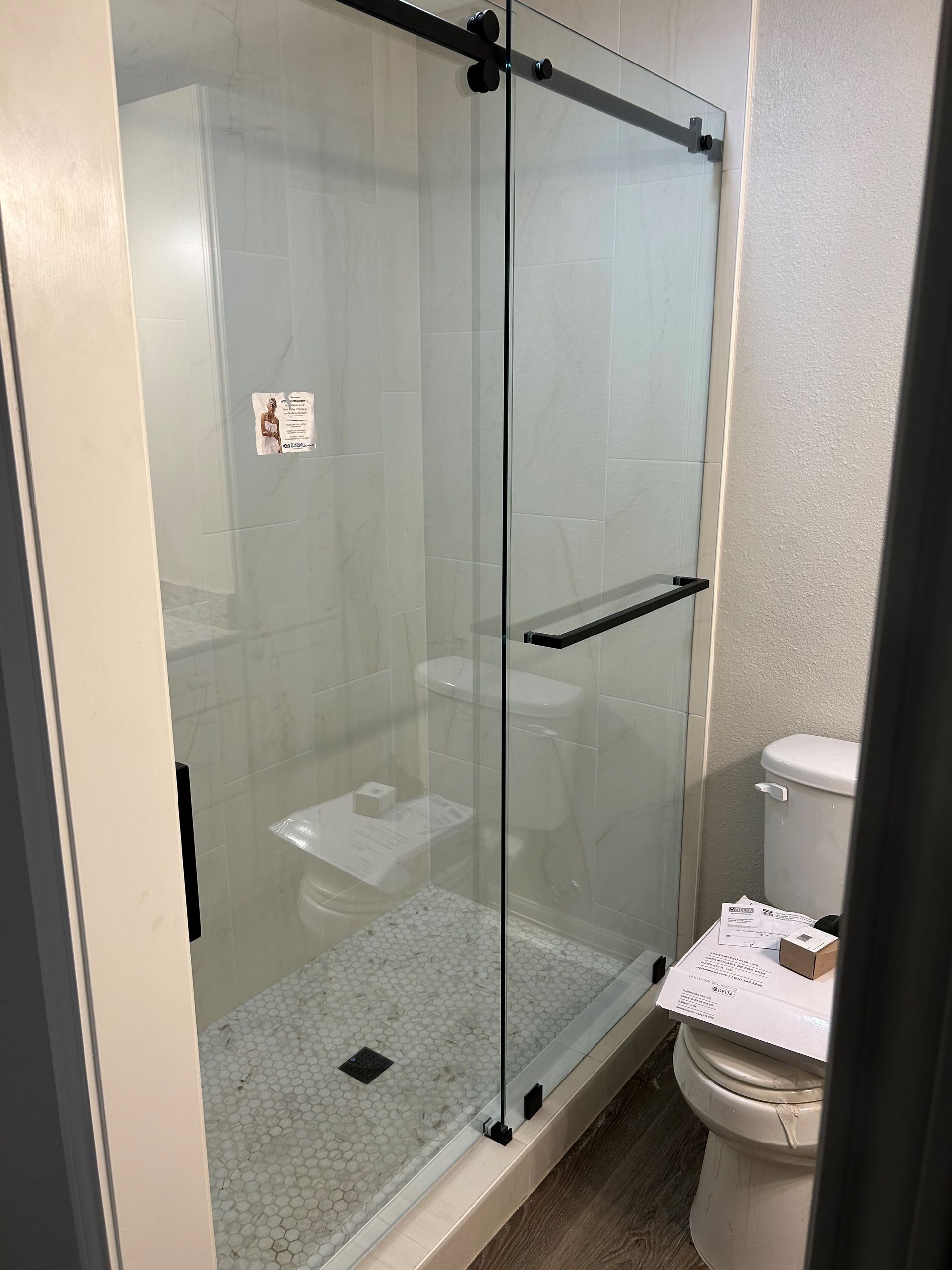 A bathroom with a sliding glass shower door and a toilet.