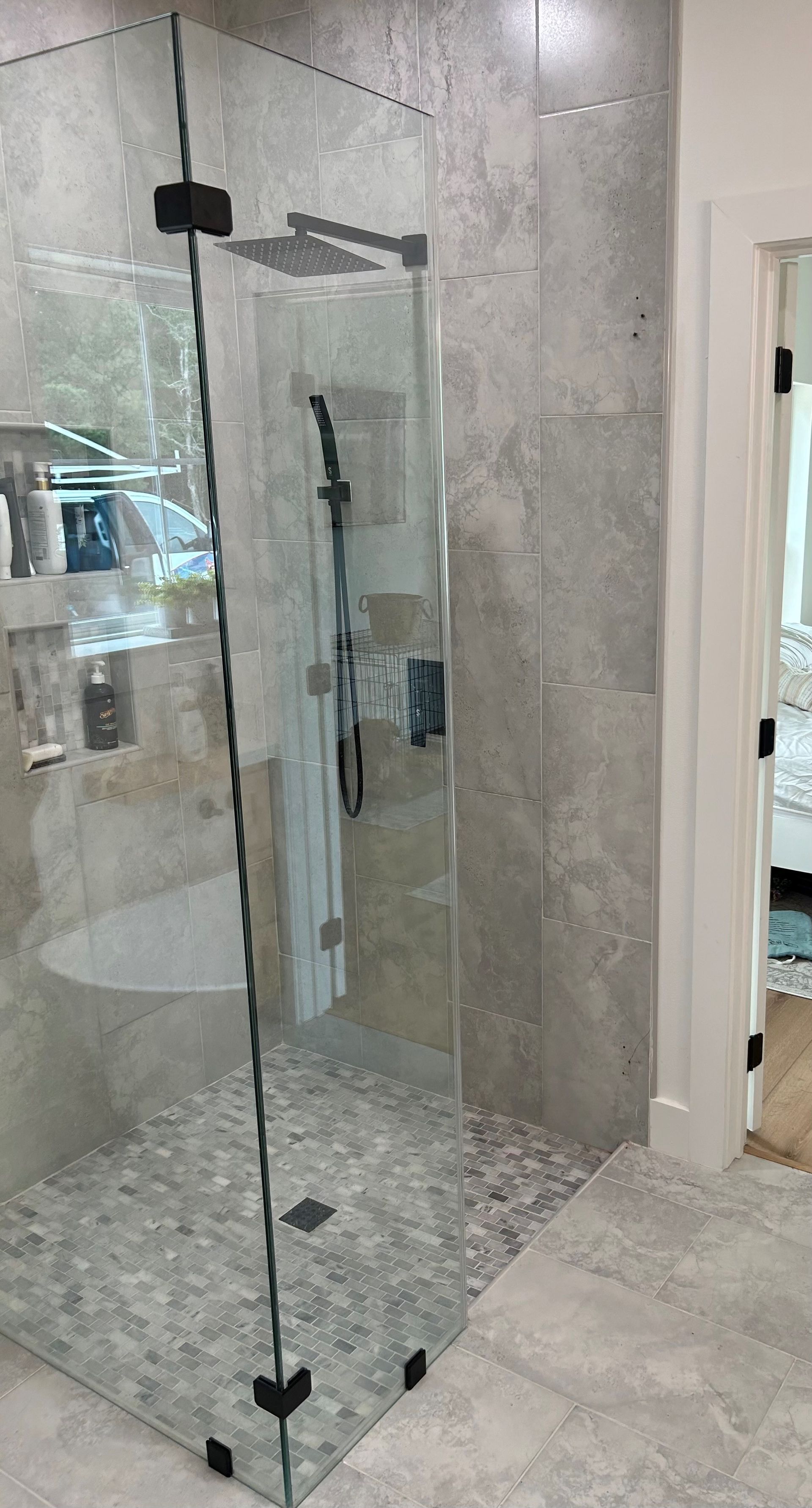 A bathroom with a walk in shower with a glass door.