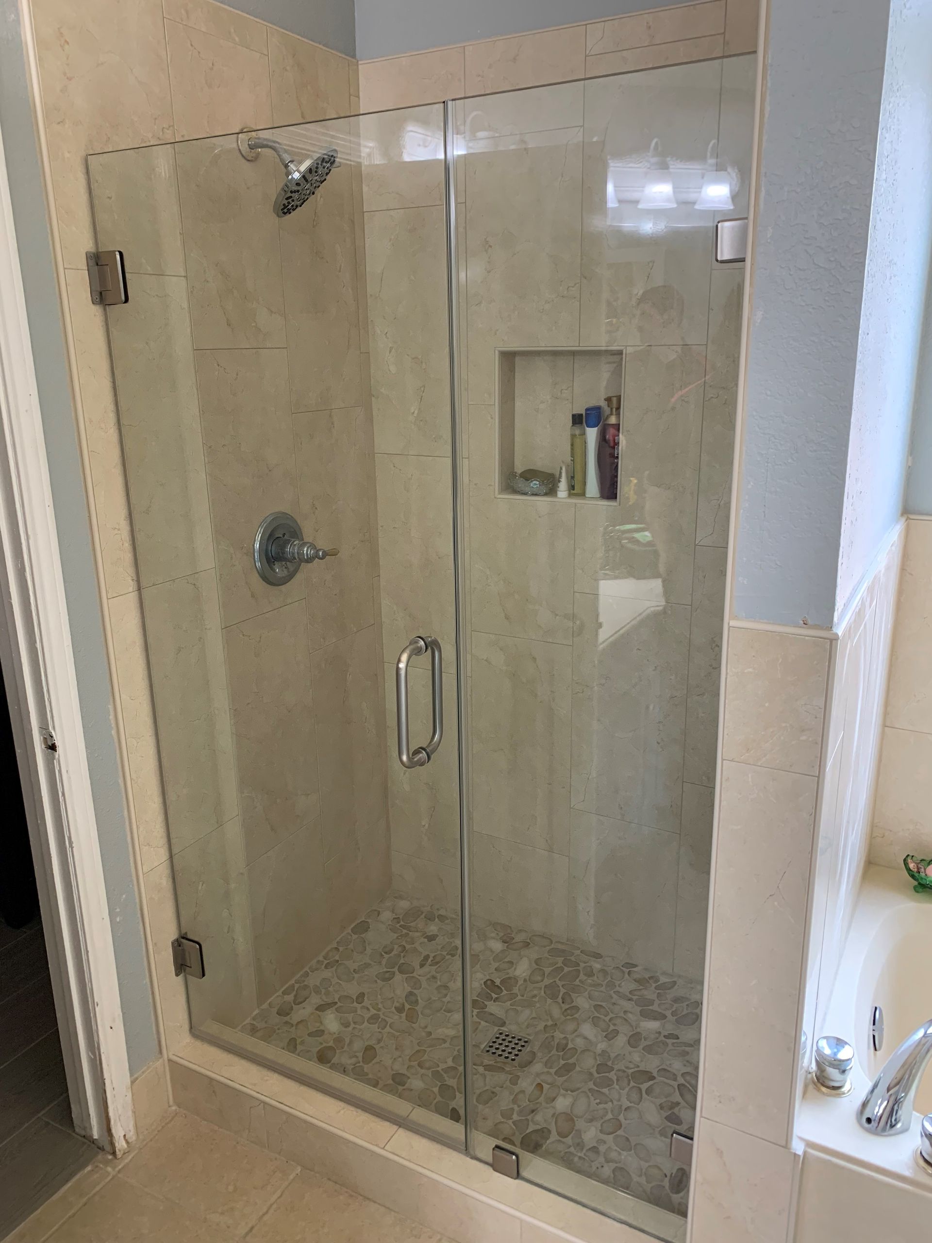 A bathroom with a walk in shower with a glass door.