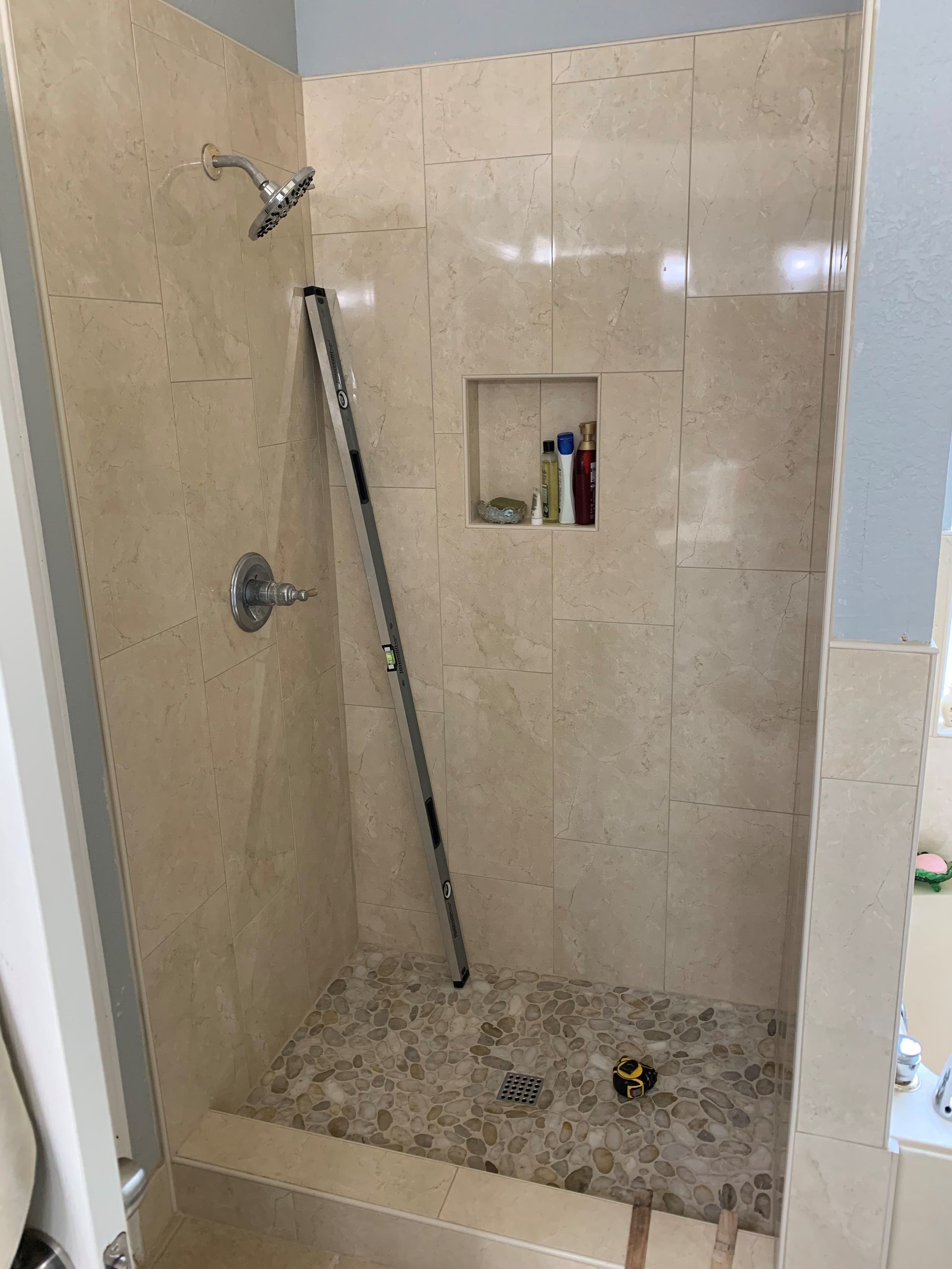 A bathroom with a walk in shower and a shelf.