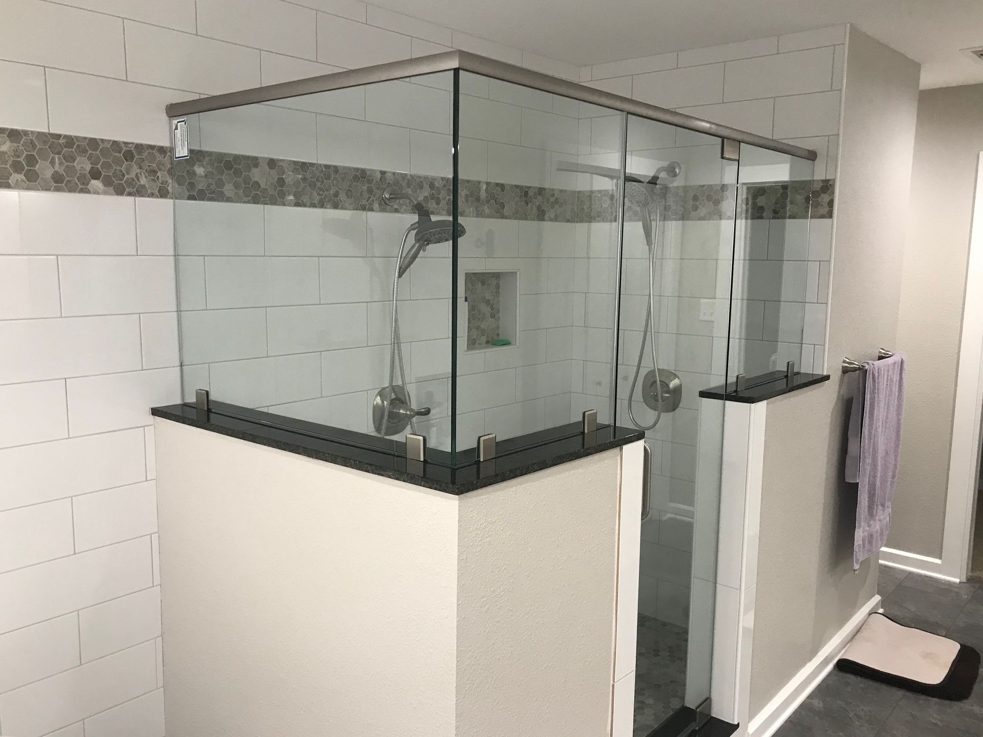 A bathroom with a walk in shower with a glass door.