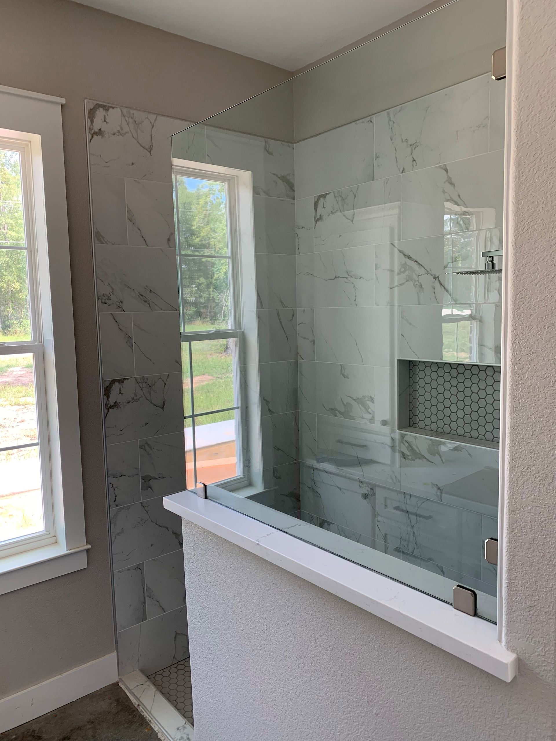 A bathroom with a walk in shower and a window.