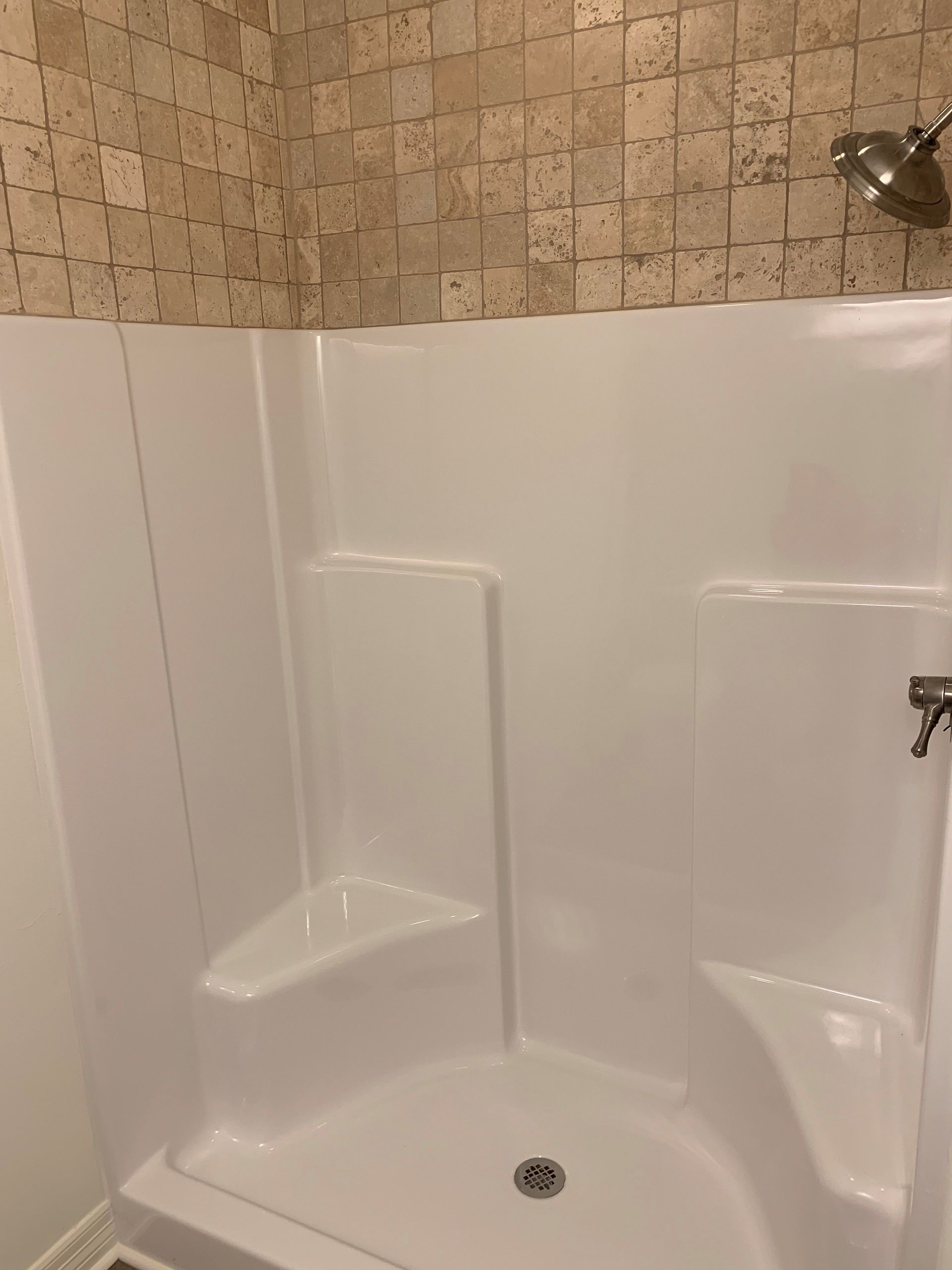 A shower stall with a seat and a shower head in a bathroom.