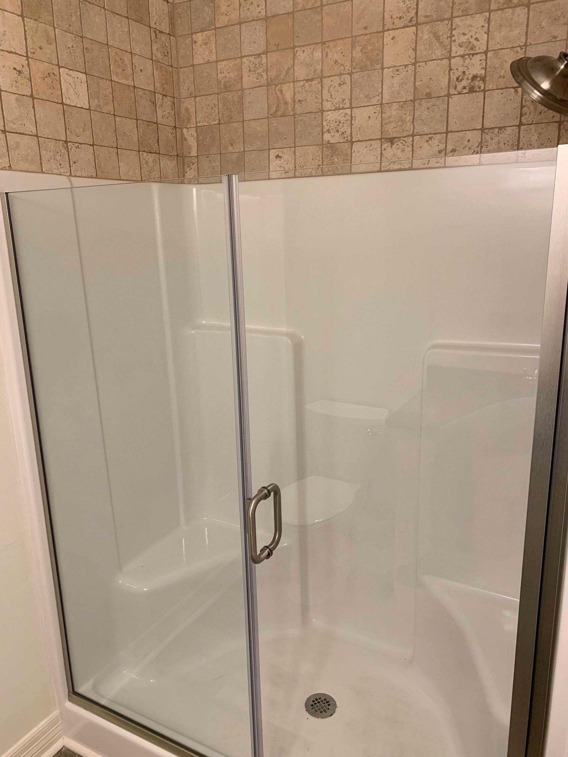 A bathroom with a walk in shower with a glass door.