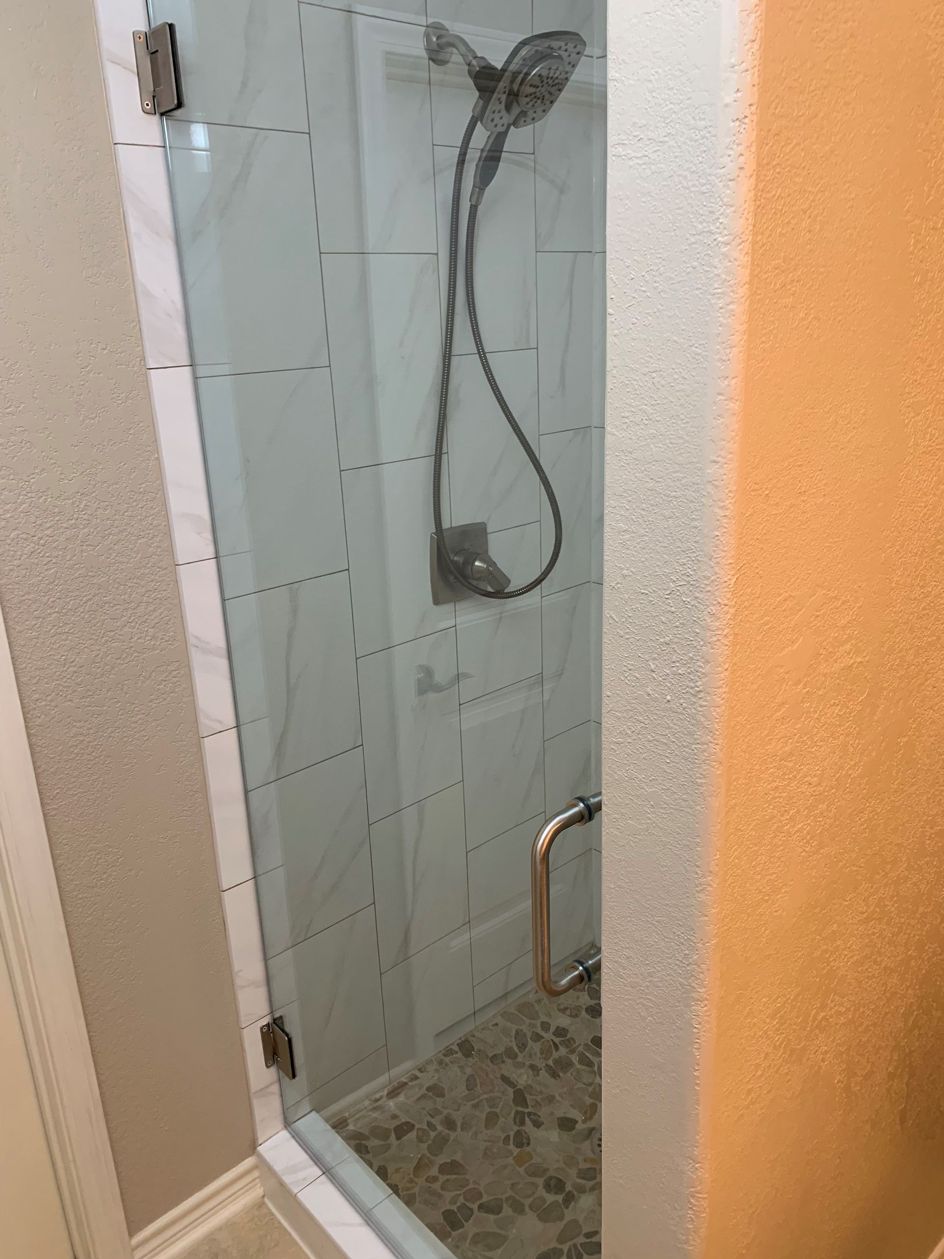 A shower stall with a glass door and a shower head.