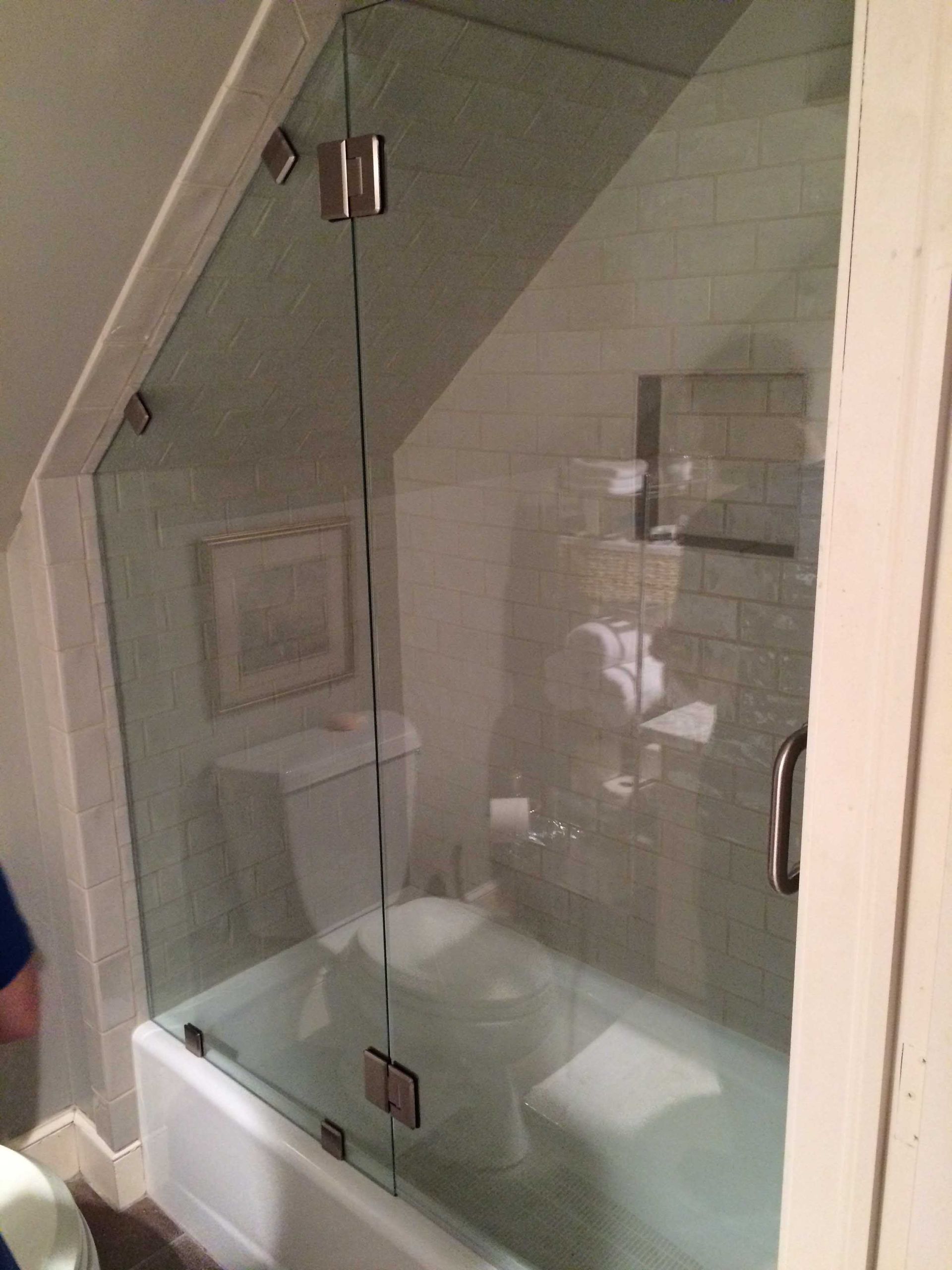 A bathroom with a bathtub and toilet and a glass shower door.