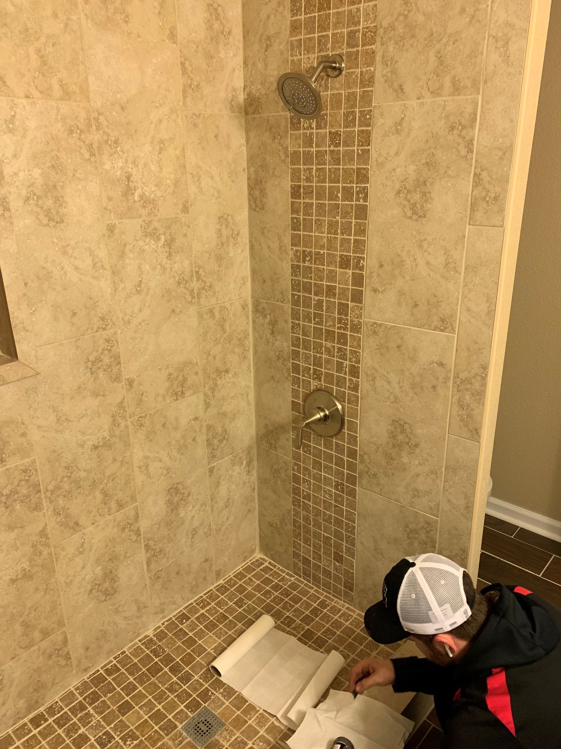 A man is working on a shower in a bathroom.