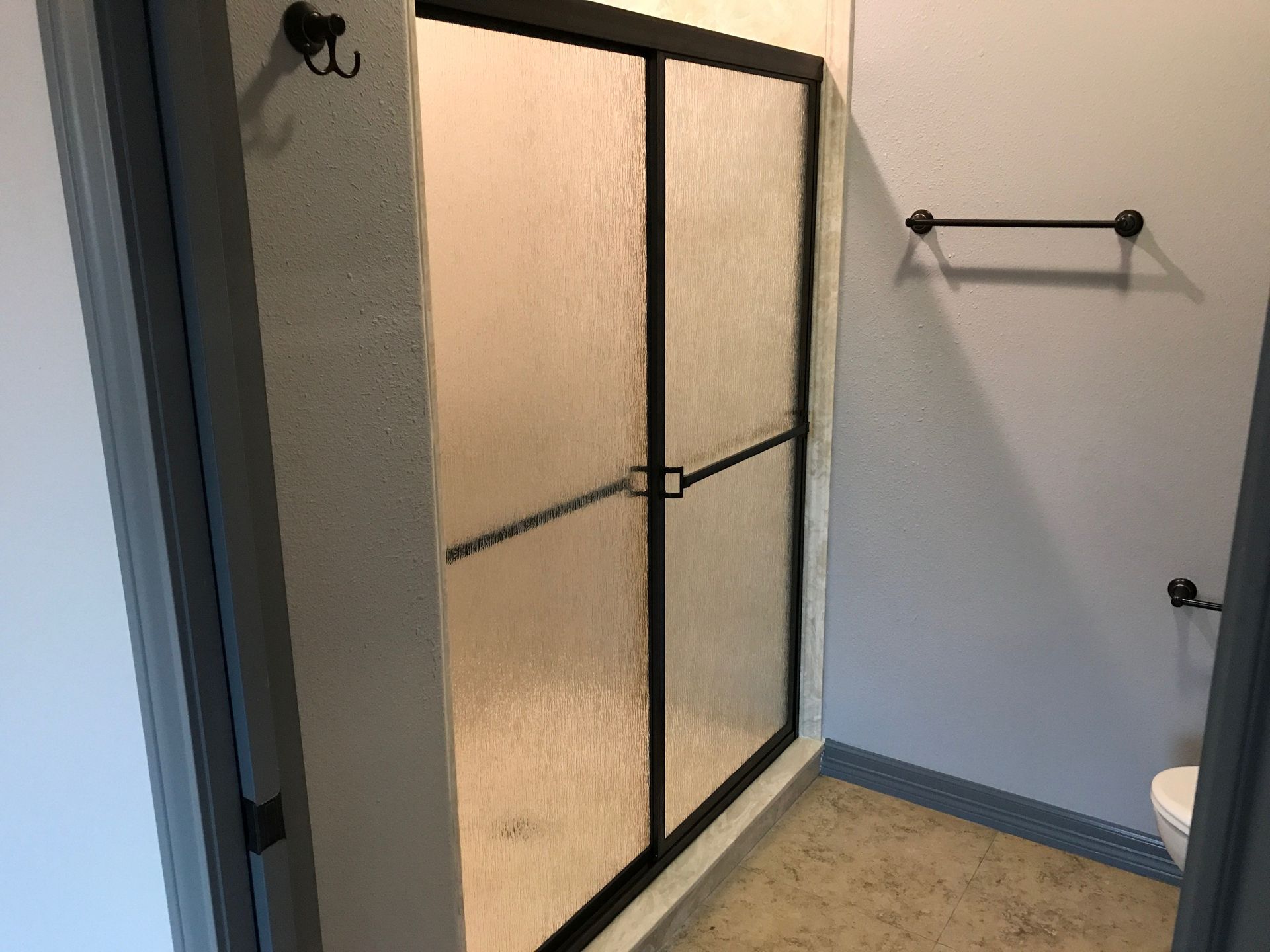 A bathroom with a sliding glass shower door and a toilet.
