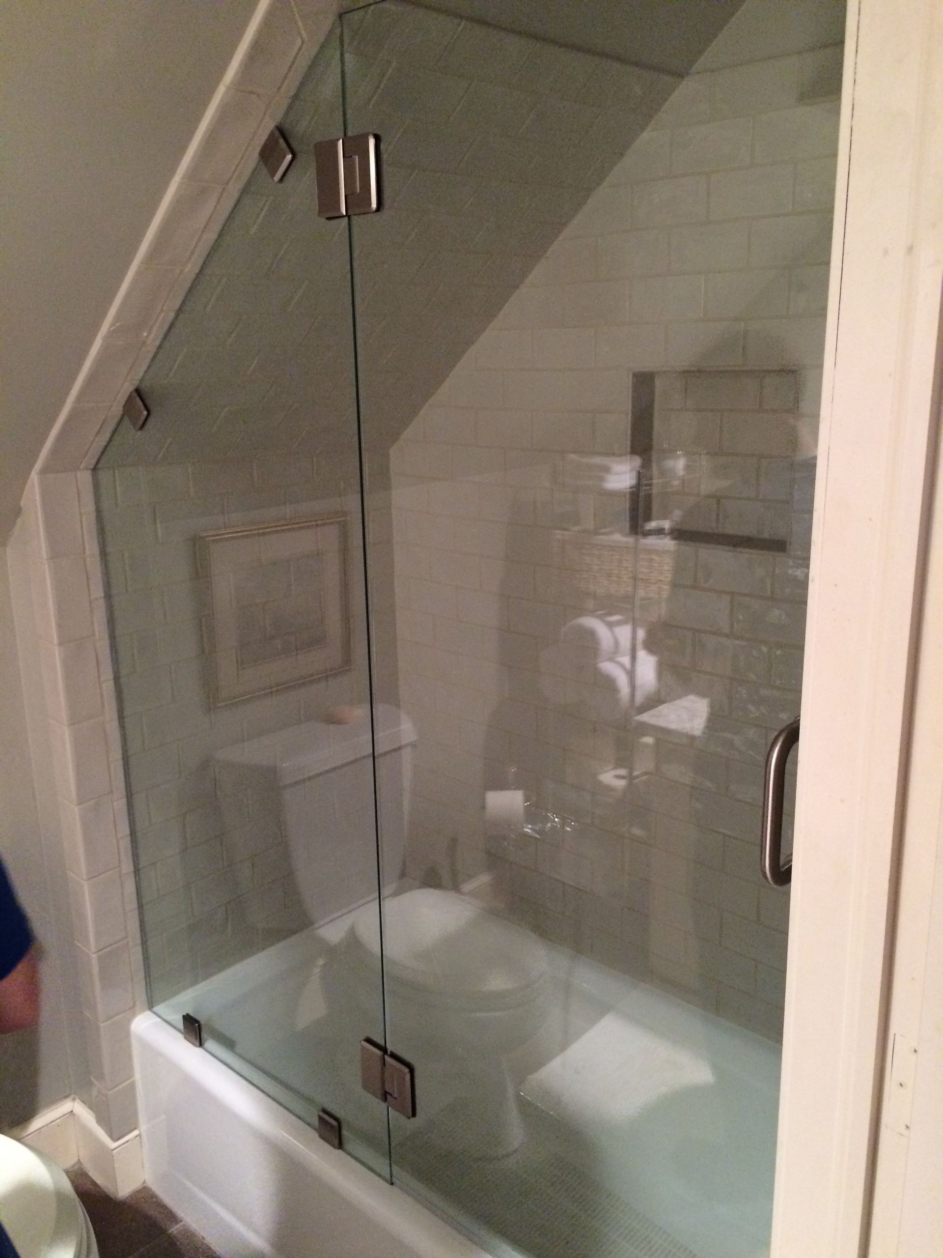 A bathroom with a bathtub and toilet and a glass shower door