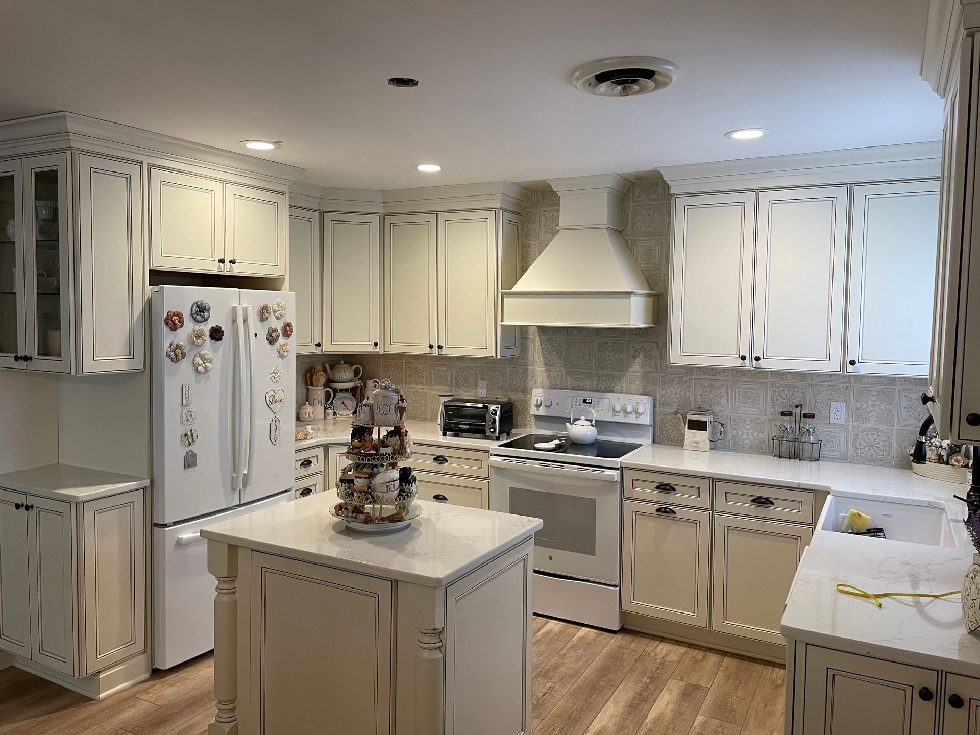 A kitchen with white cabinets, a refrigerator, and a stove