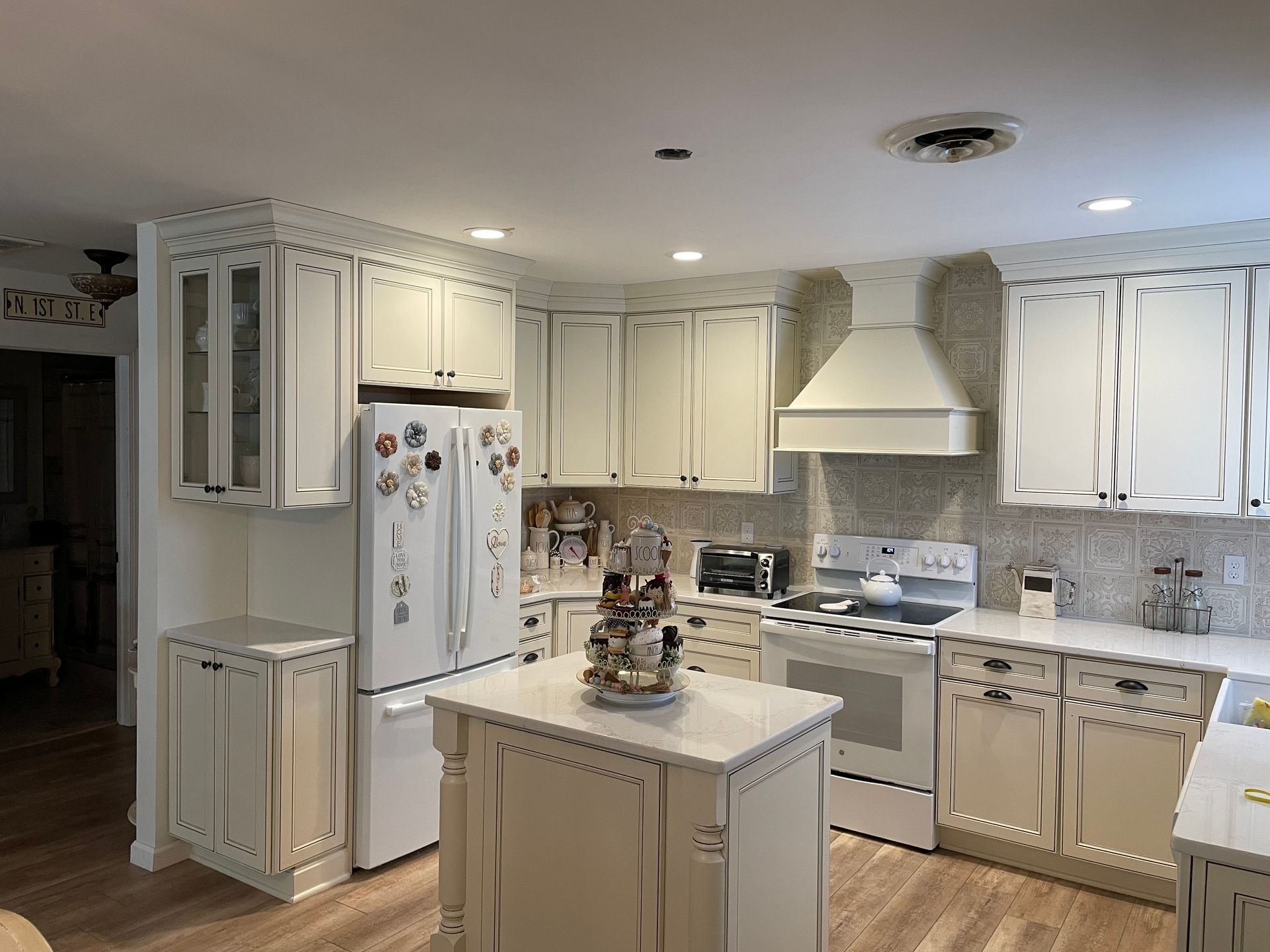 A kitchen with white cabinets, white appliances, and a small island