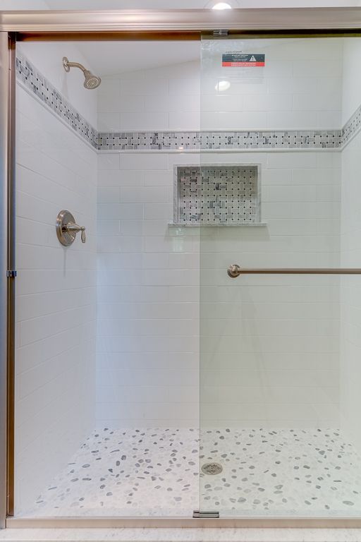A shower with a sliding glass door and a shower head