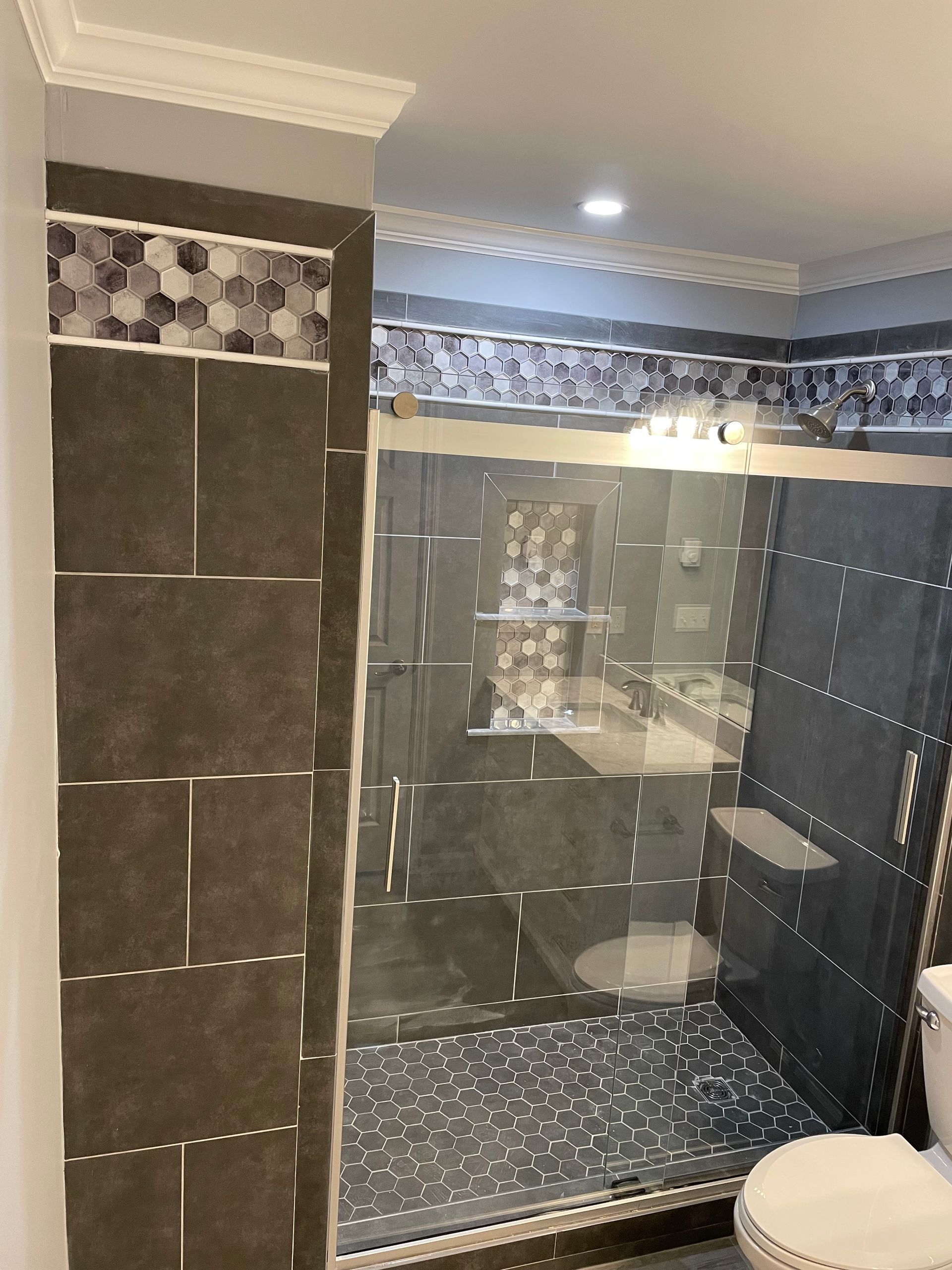 A bathroom with a walk-in shower and a toilet with glass divider