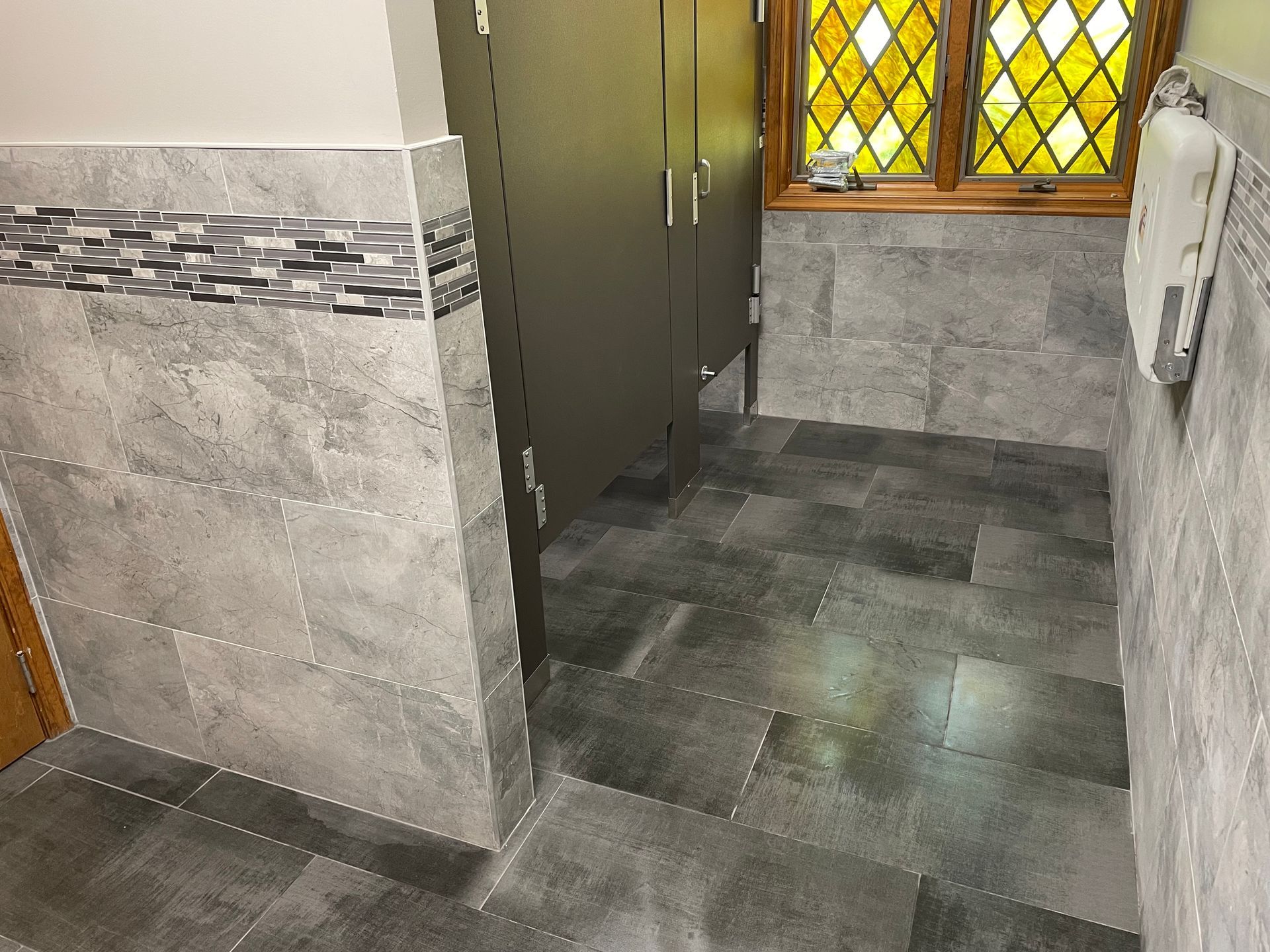 A bathroom with a stained glass window and a gray tile floor
