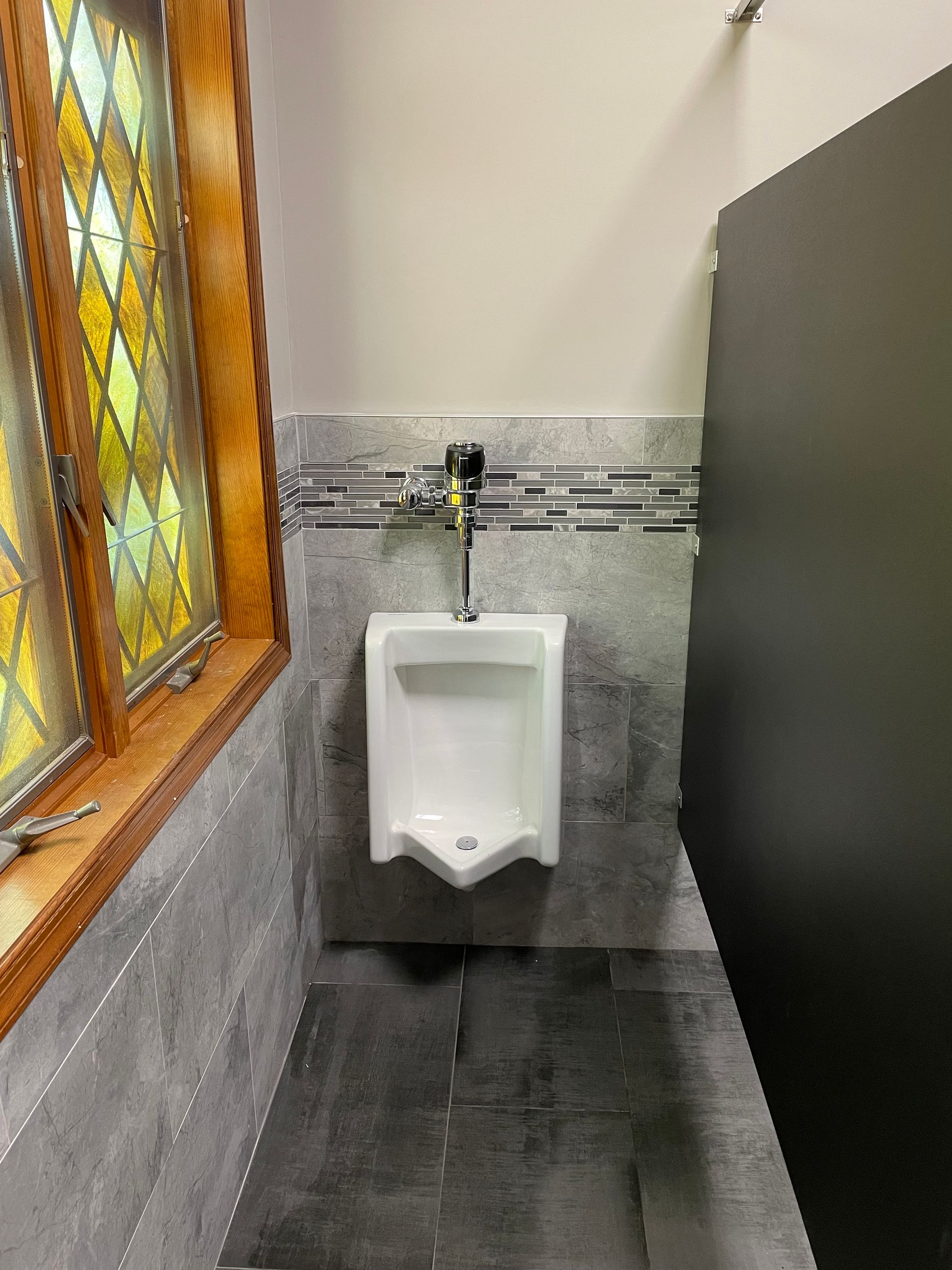 A bathroom with a urinal and a stained glass window