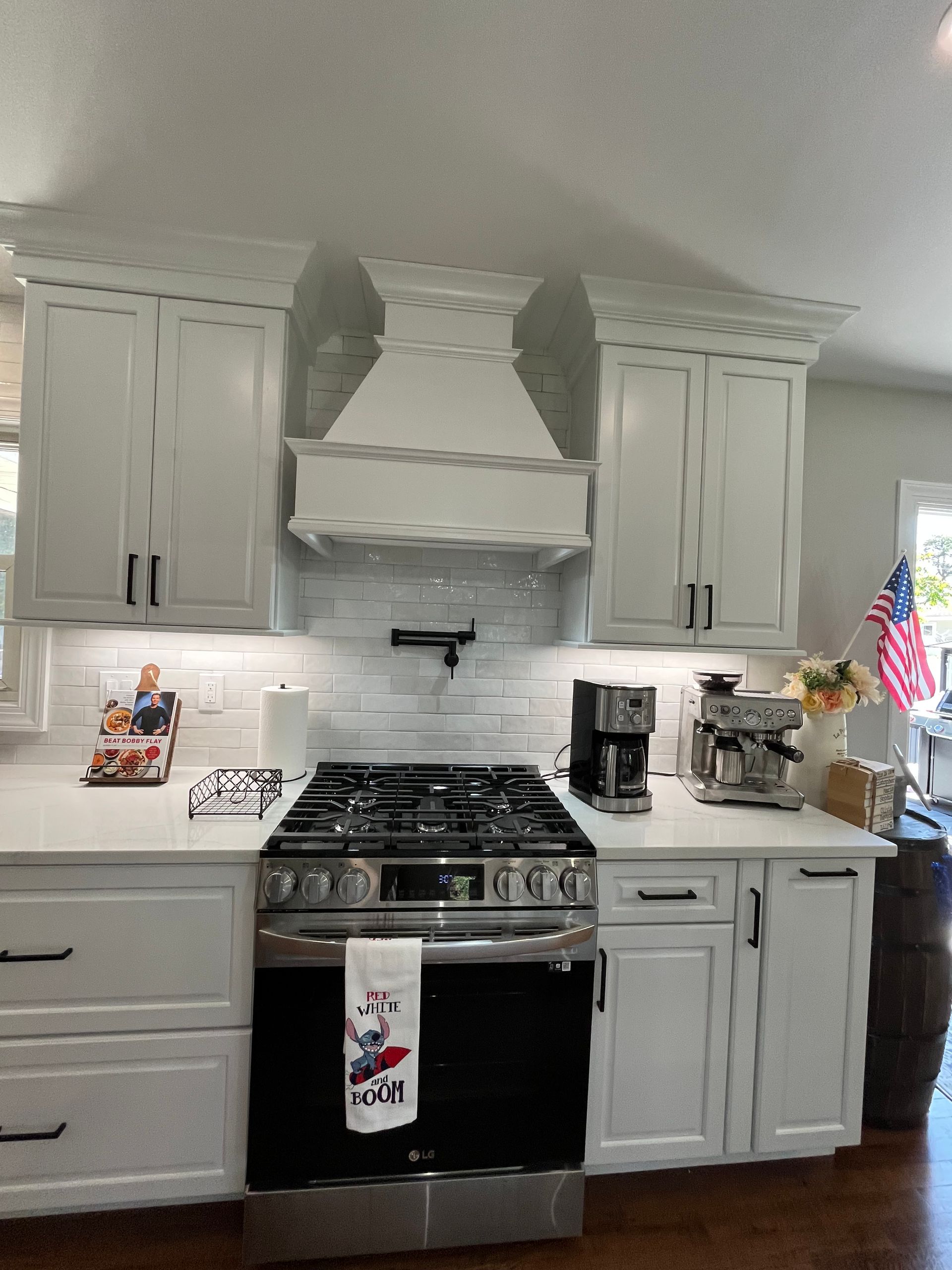 A kitchen with white cabinets, a stove, and a coffee maker