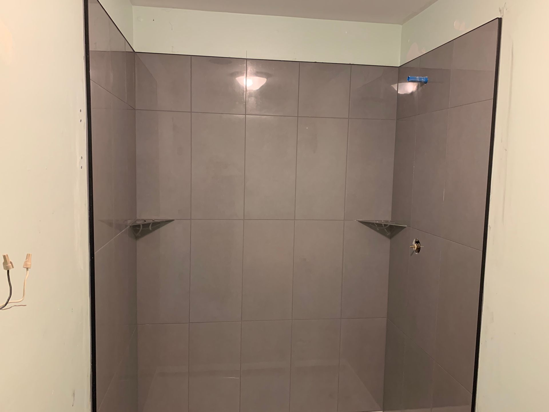 A bathroom with gray tiles and a shower stall