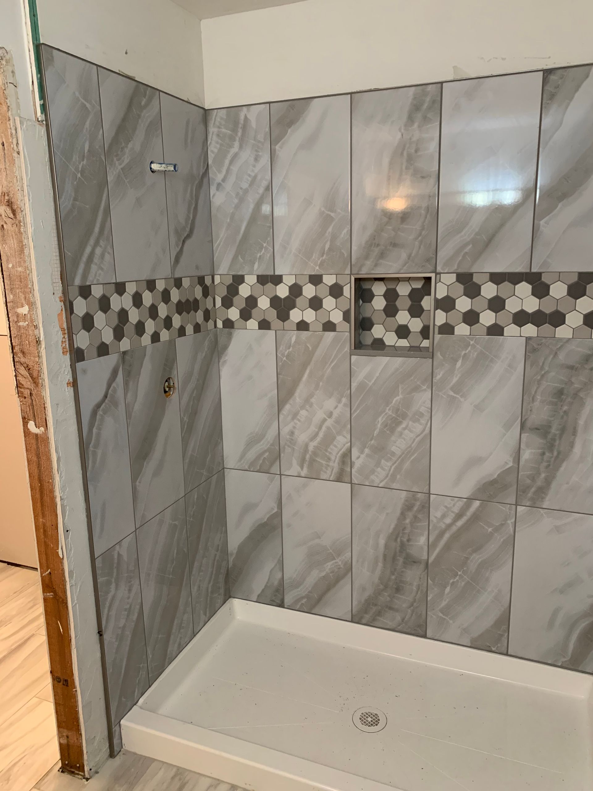 A bathroom with a shower stall and gray tiles