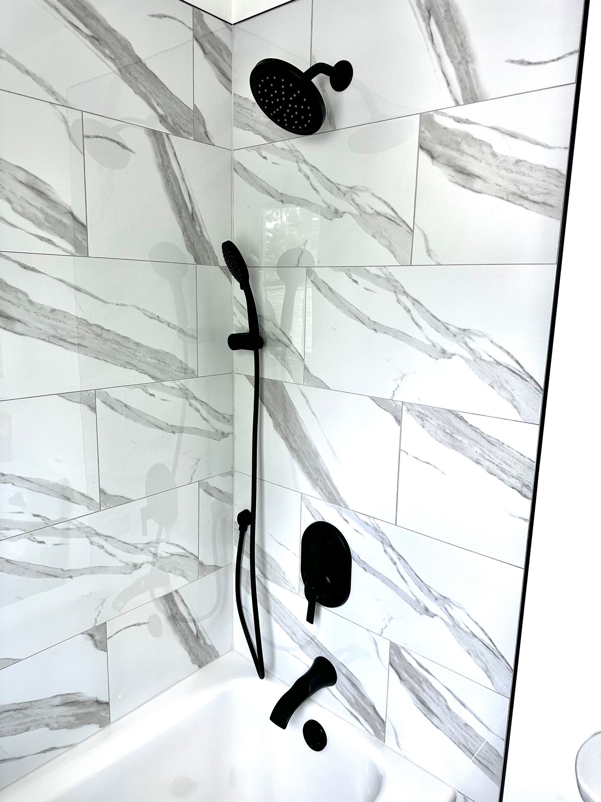 A bathroom with marble tiles and a black shower head