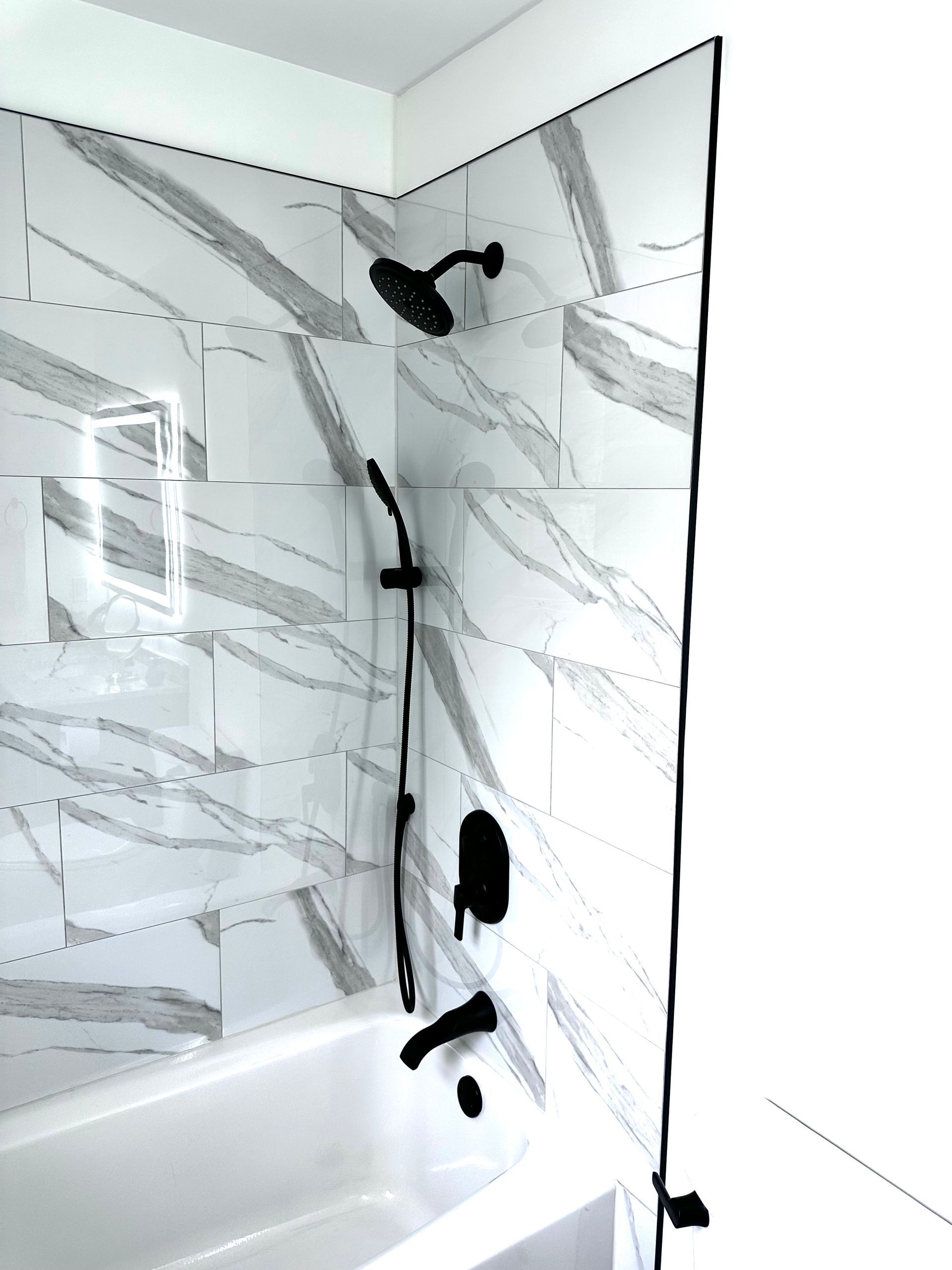 A bathroom with marble tiles and a bathtub and shower