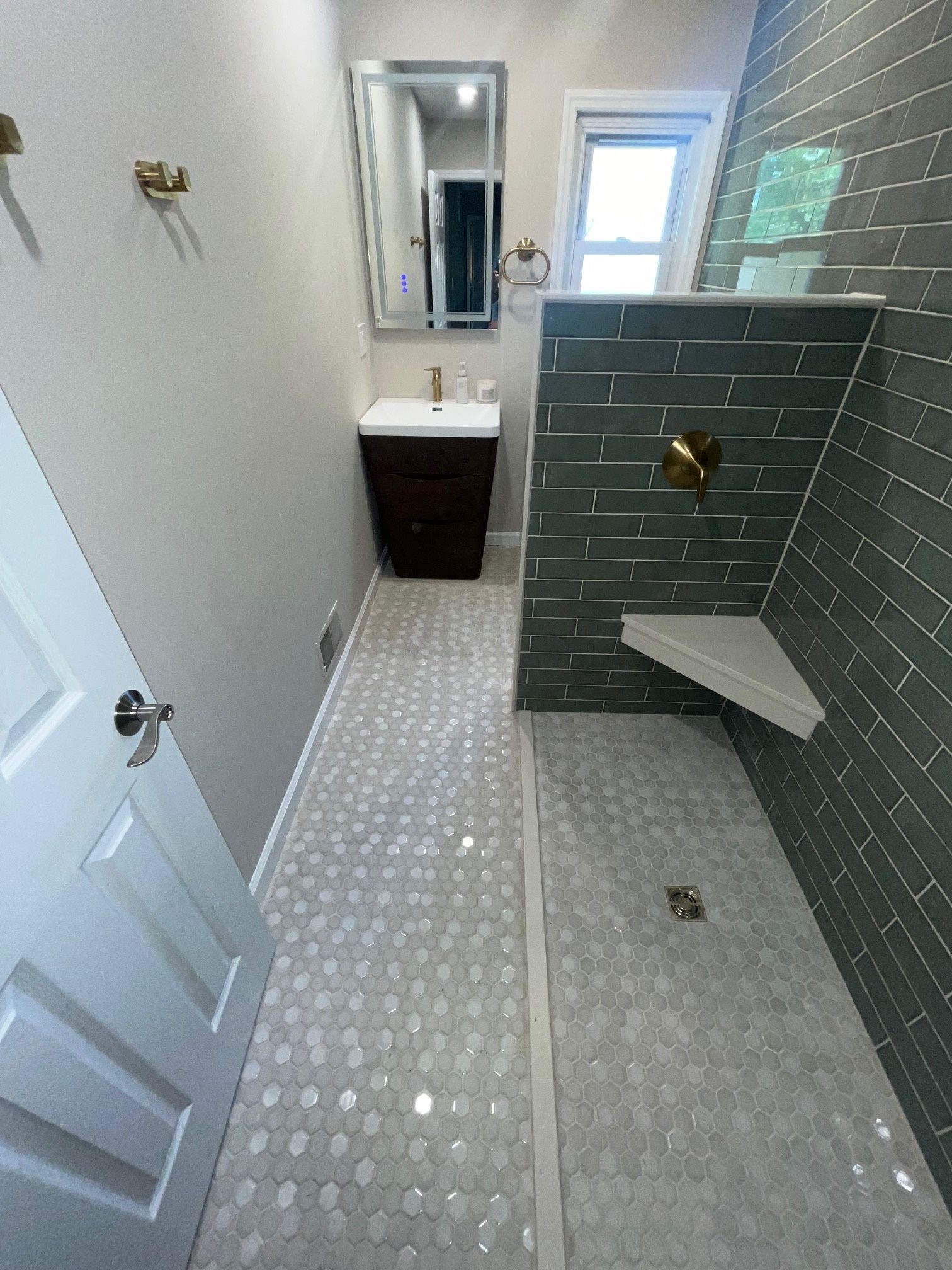 A bathroom with a walk-in shower, sink, and mirror