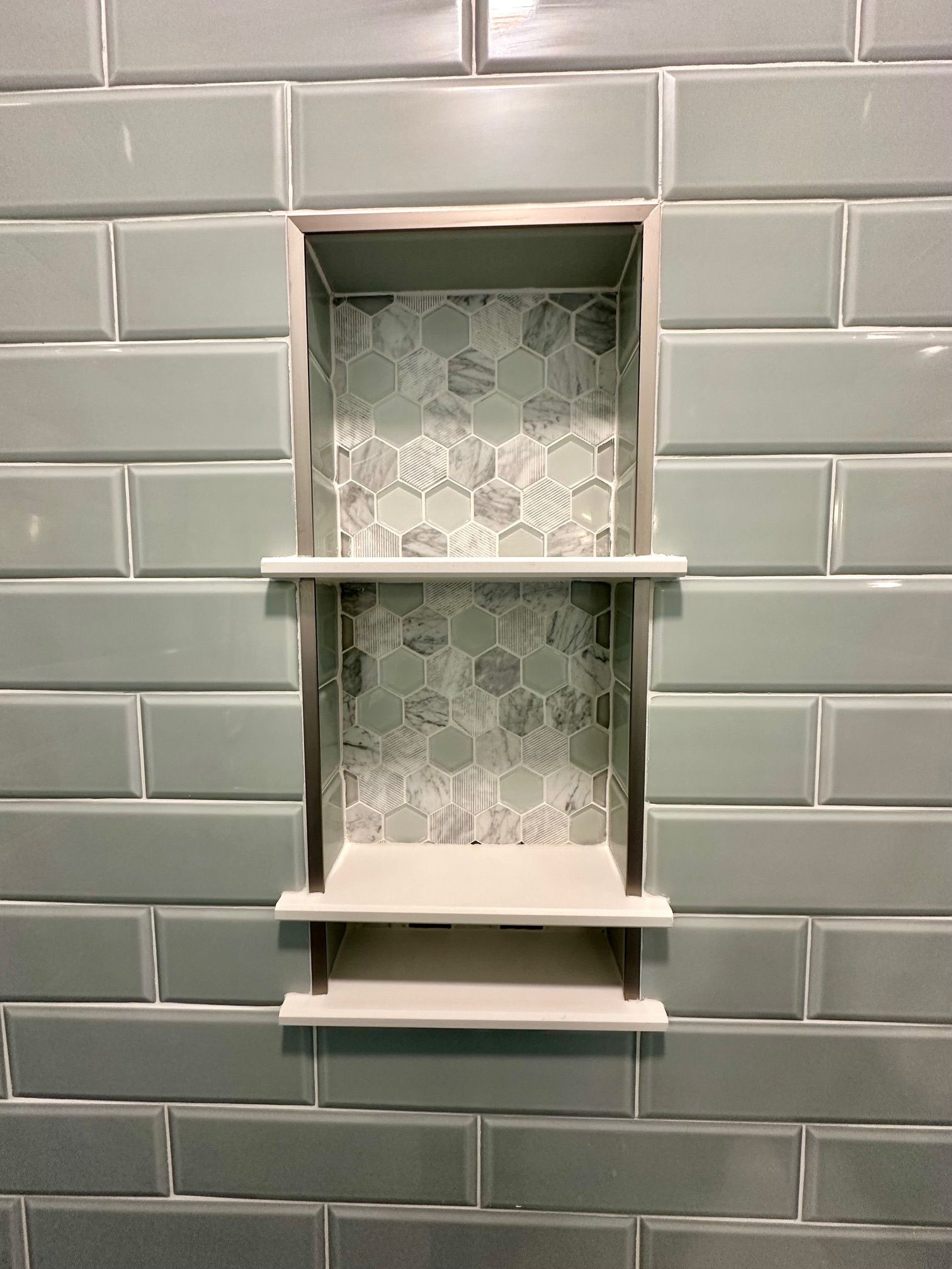 A shower niche is built into a brick wall in a bathroom