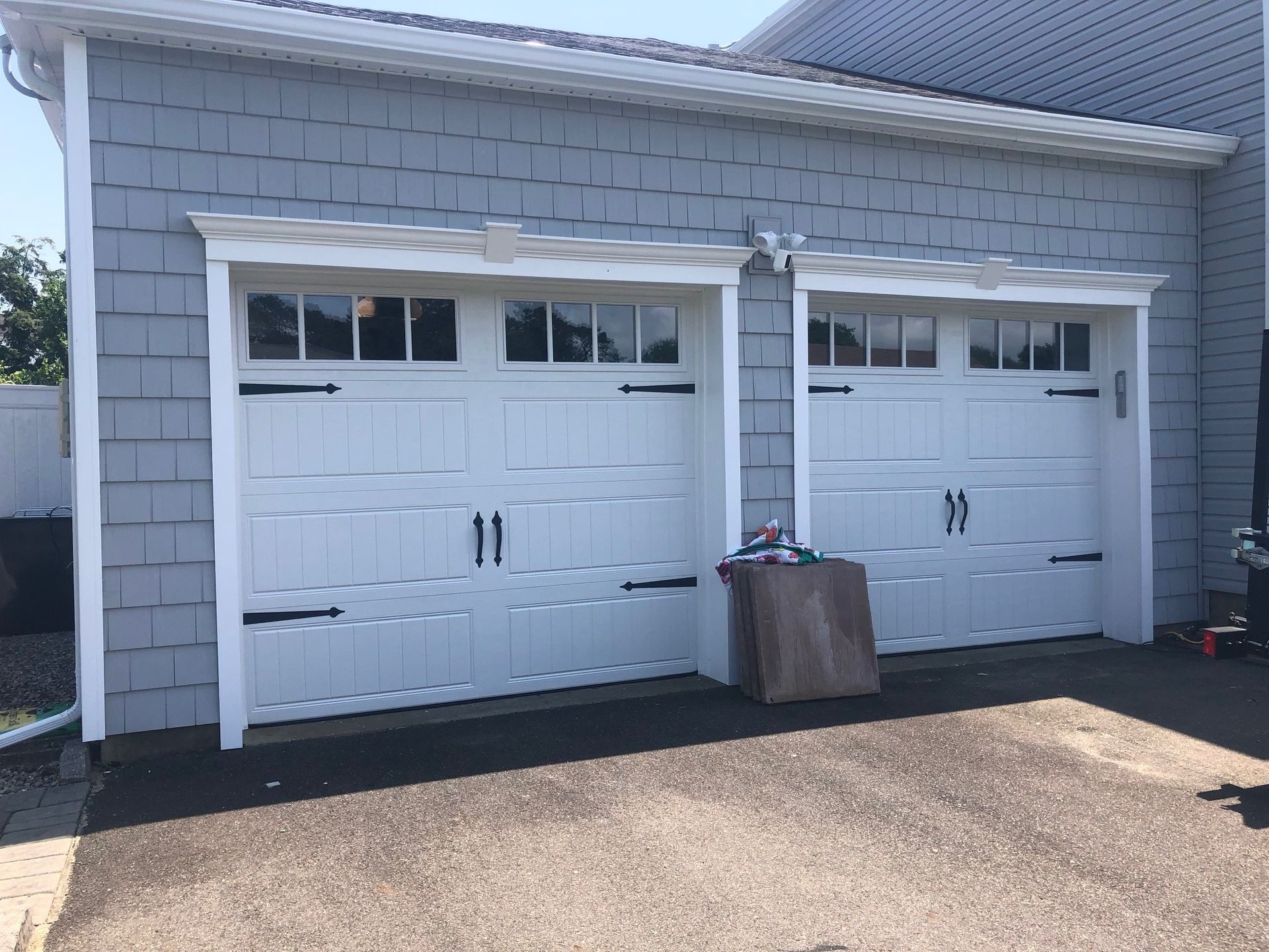 There are two white garage doors on the side of a house