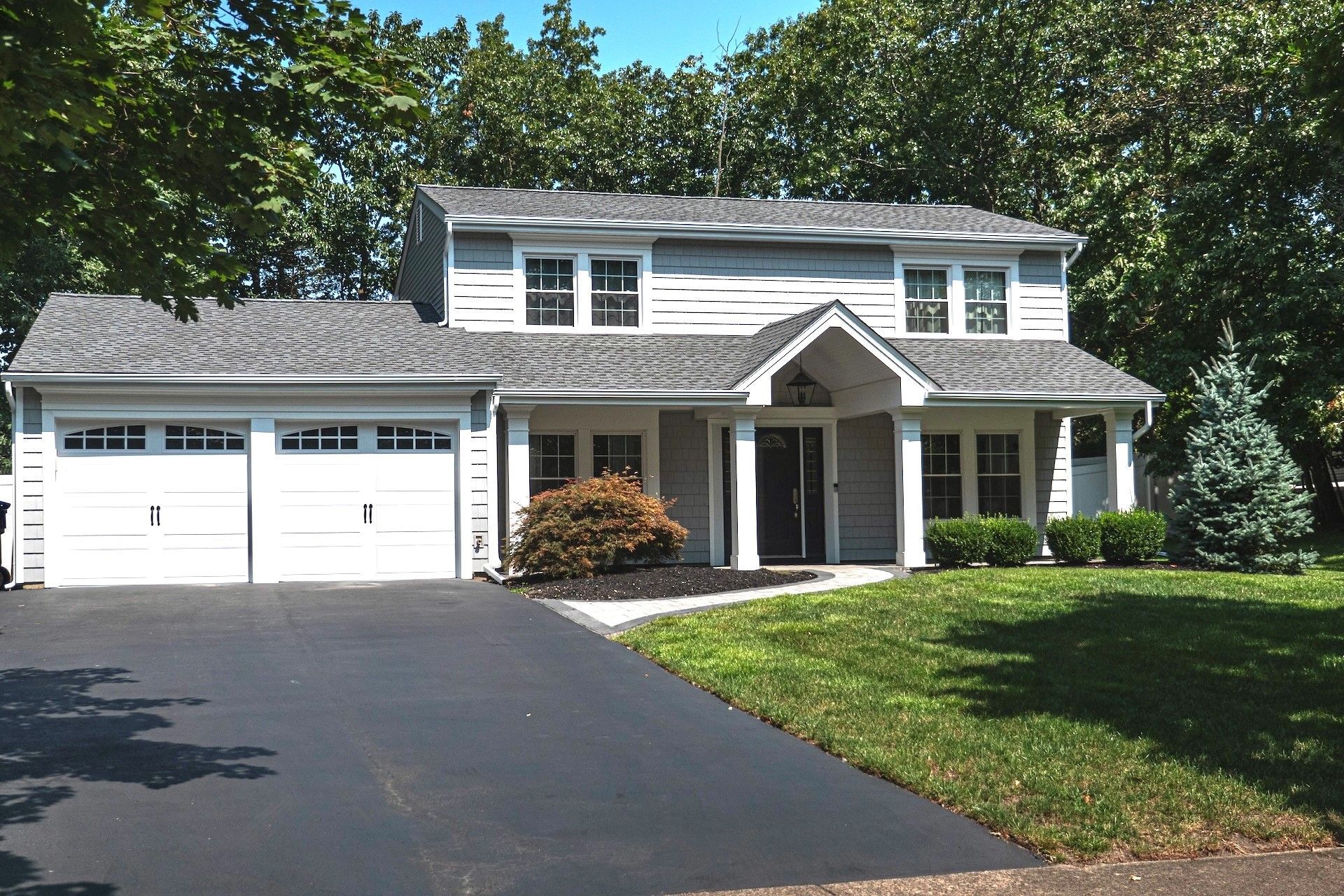 A large white house with two garage doors and a driveway