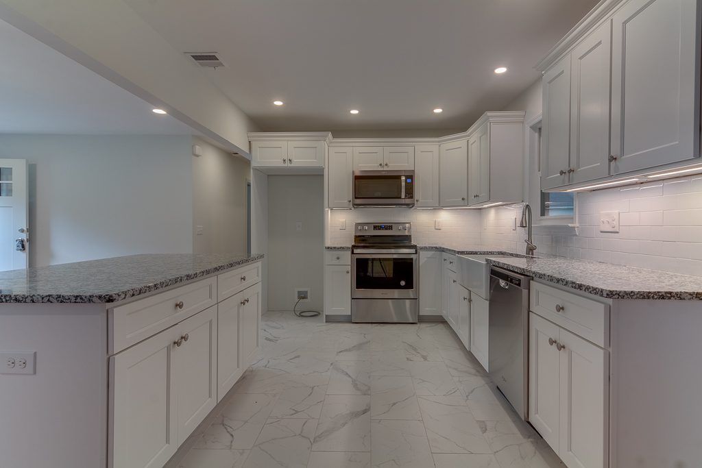 An empty kitchen with white cabinets and granite counter tops