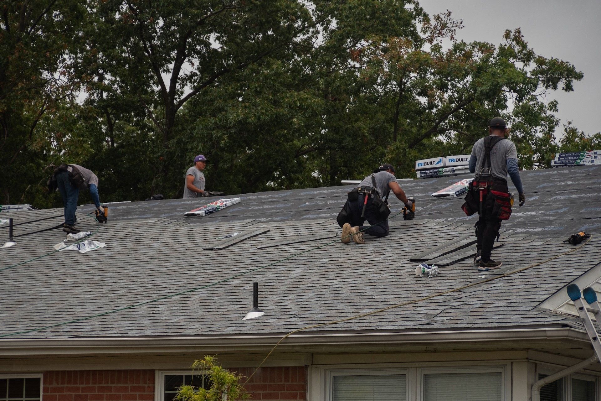 A group of men are working on the roof of a house.