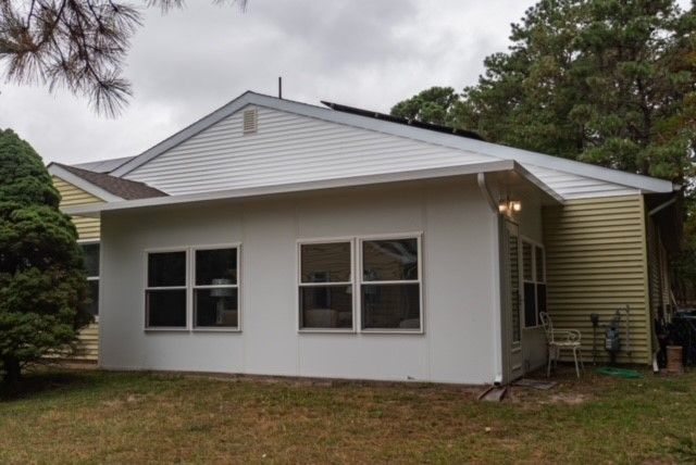 The back of a house with a white roof and a lot of windows.