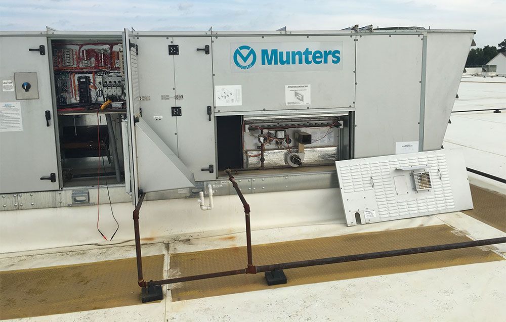 HVAC unit on a rooftop. The unit is partially open, with some panels removed for servicing.