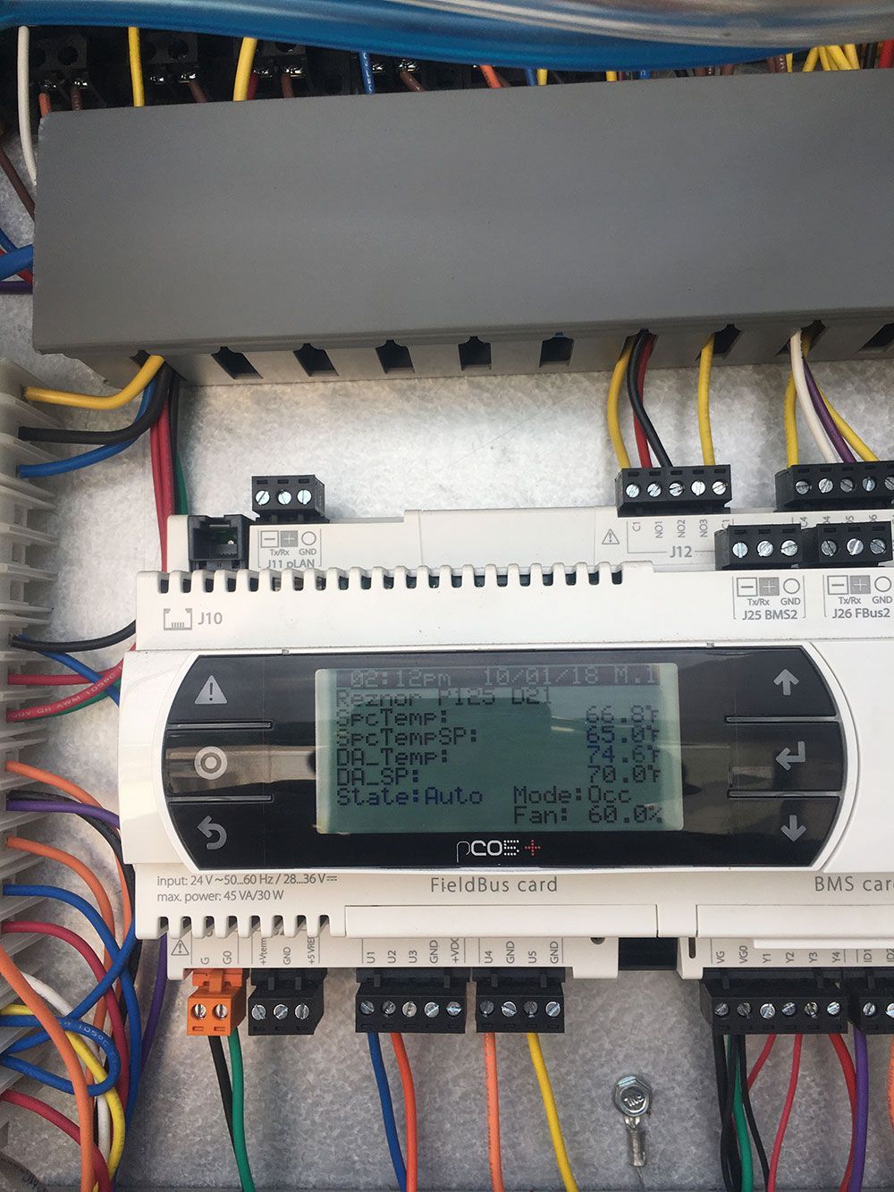 An electrical panel with a control screen displaying temperature readings and connected wires.