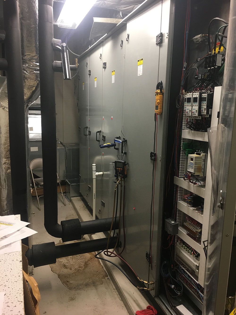HVAC system with pipes, metal panels, and control panel in an industrial setting.
