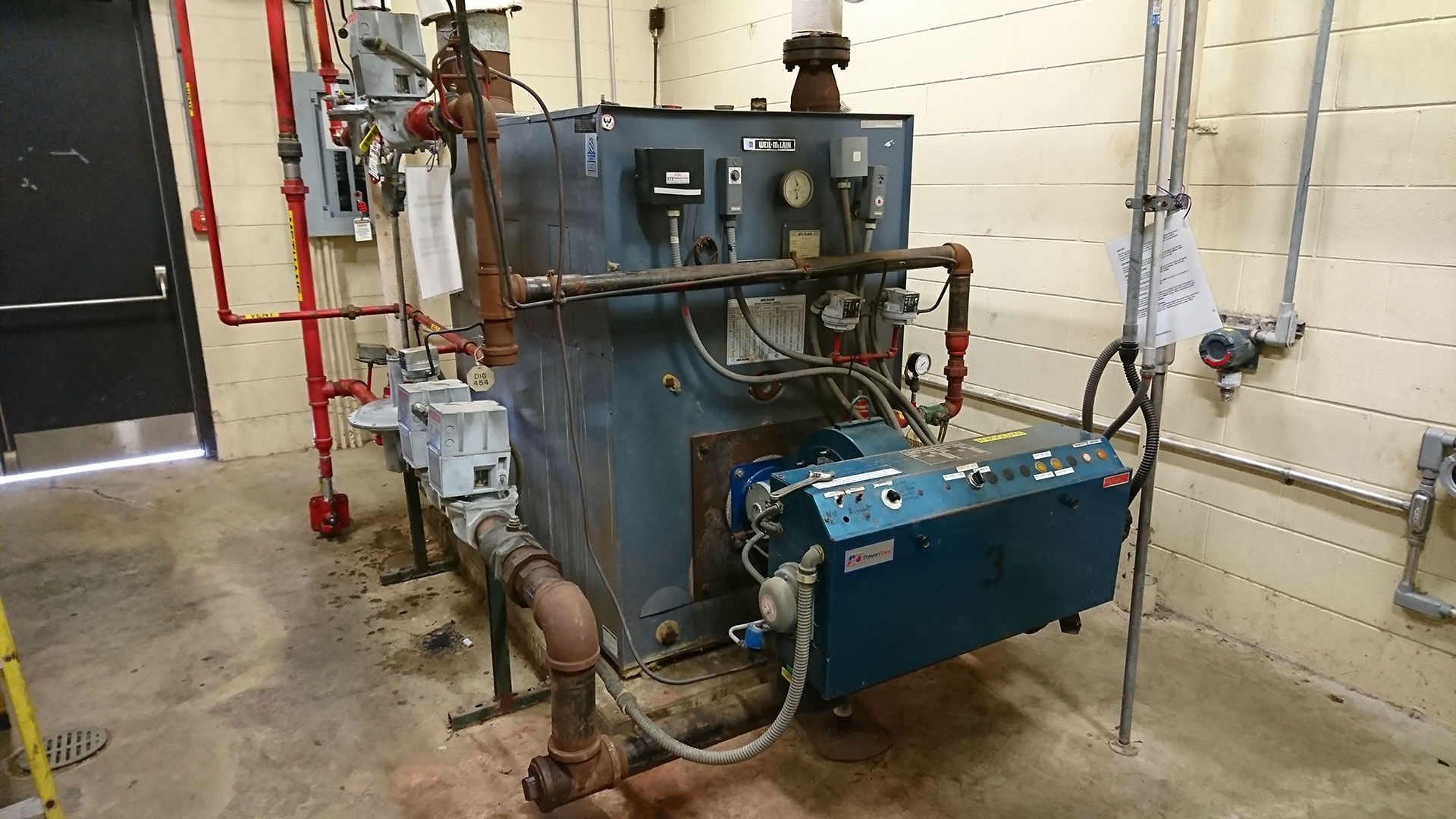 Industrial boiler in a utility room with pipes and gauges.