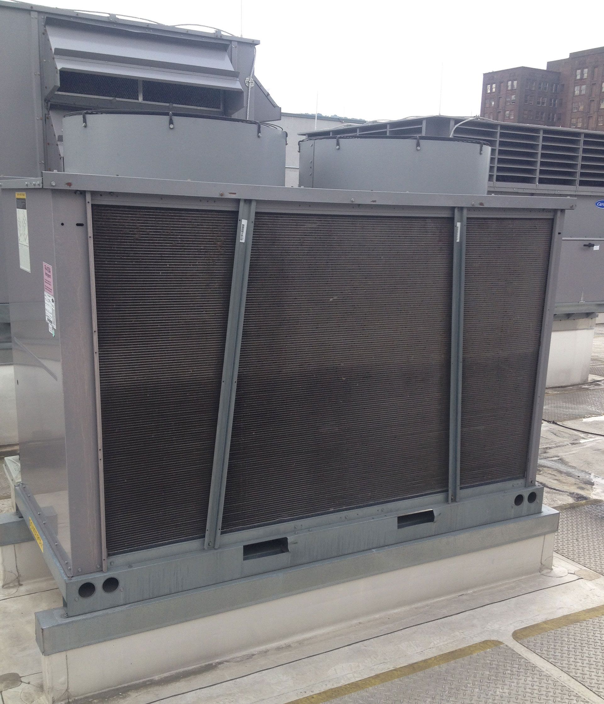 Large rooftop air conditioning unit, gray metal, with curved fins and vents.