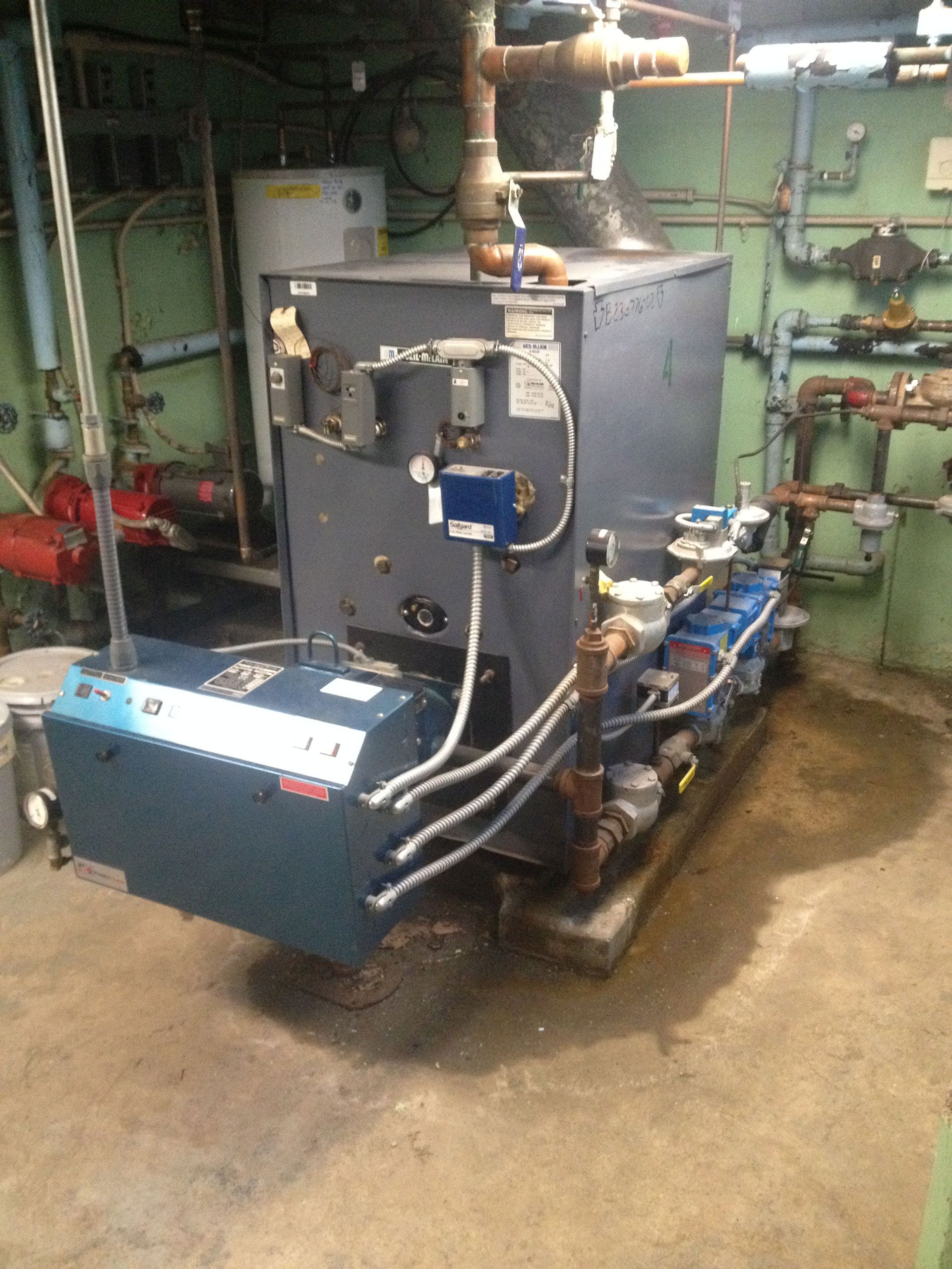 Industrial boiler in a utility room with pipes and equipment.