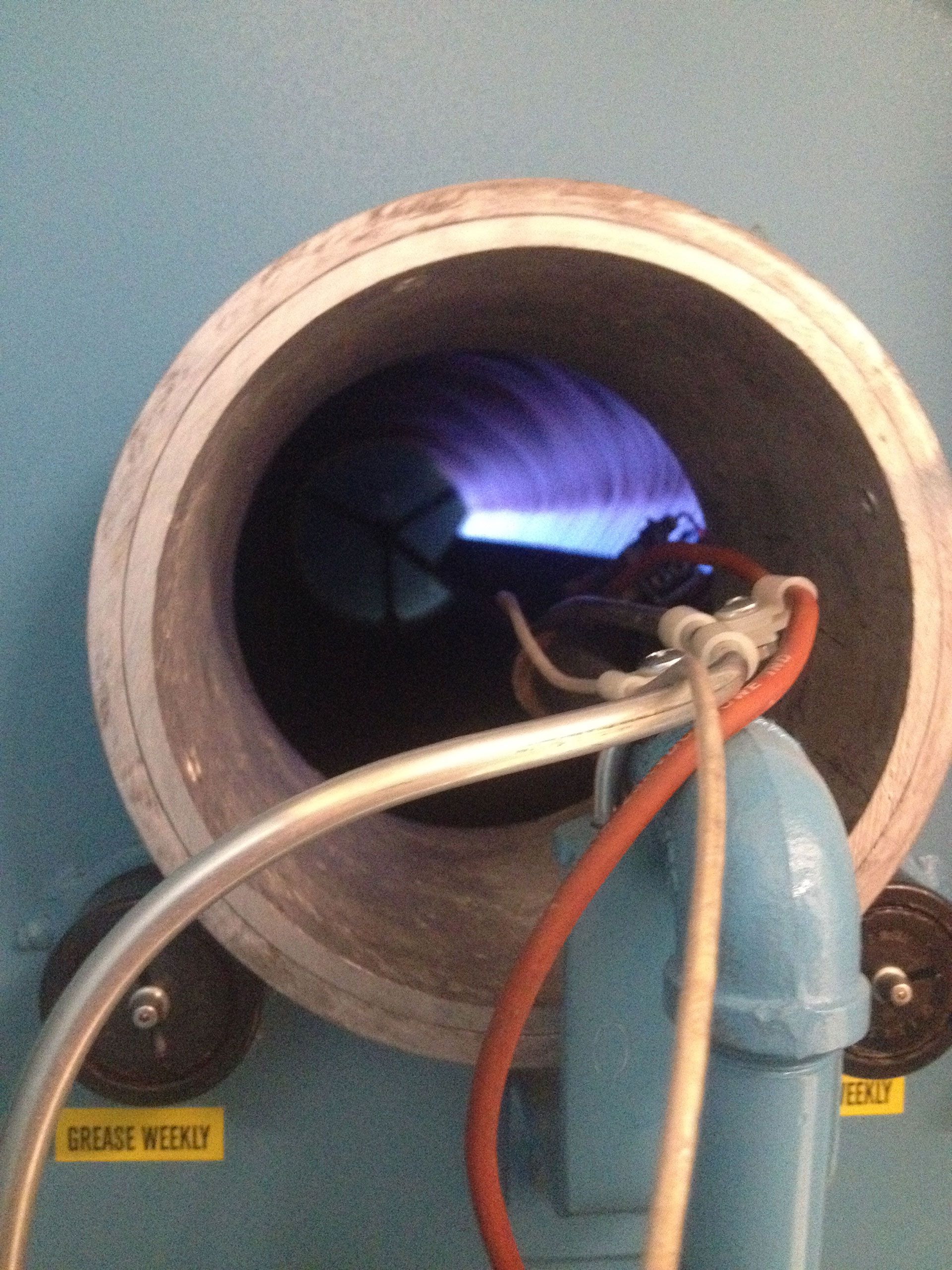 Inside a furnace, a bright blue flame emits from a nozzle, with tubes connected.