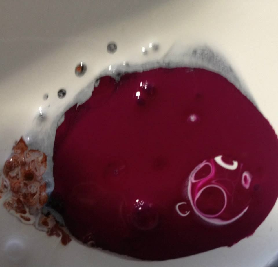 A white bowl filled with purple liquid and bubbles