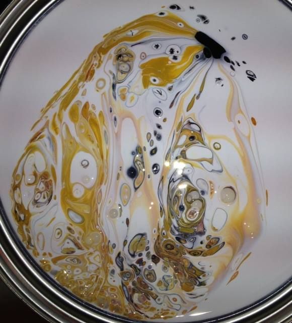 A can of paint with a swirl of yellow and white paint